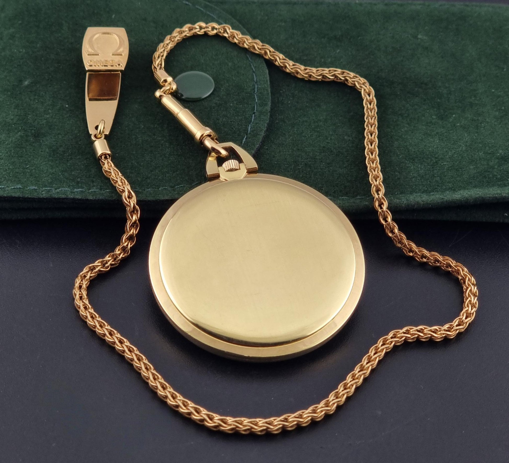 a close up of the back of a Vintage Omega De Ville Pocket Watch 1714 side profile on a dark background