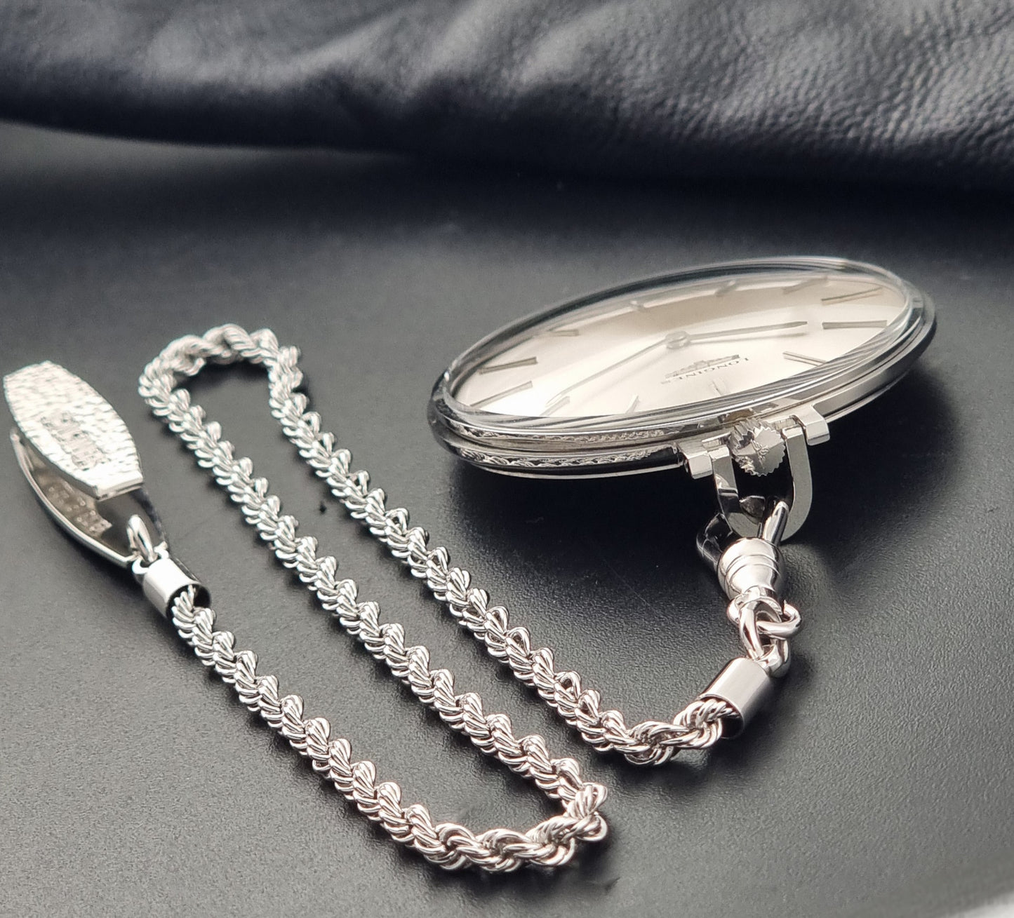 A Vintage Longines pocket watch  7713 showing the signed crown on a dark backgound