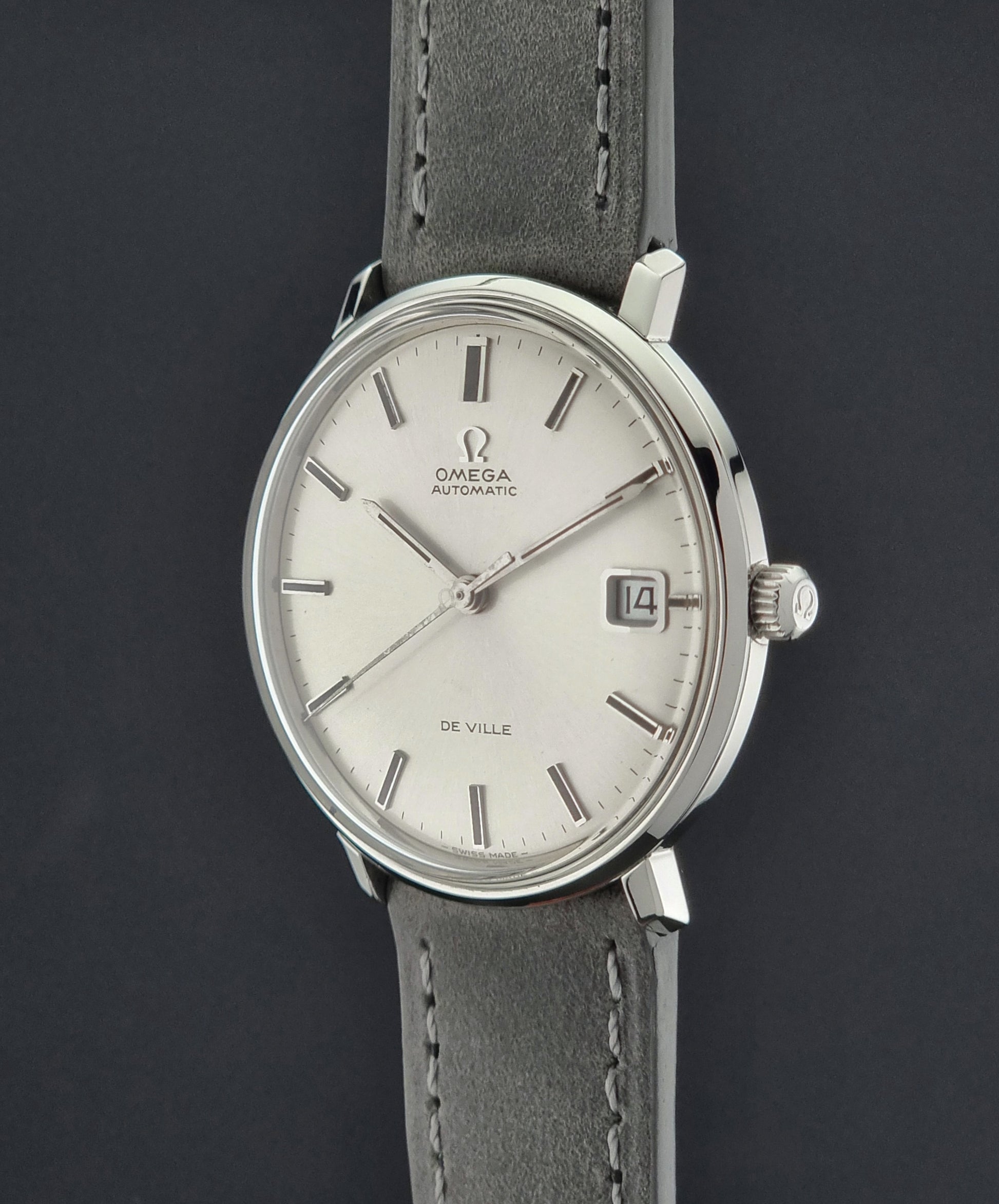Omega watch with silver dial and gray leather strap on a dark background