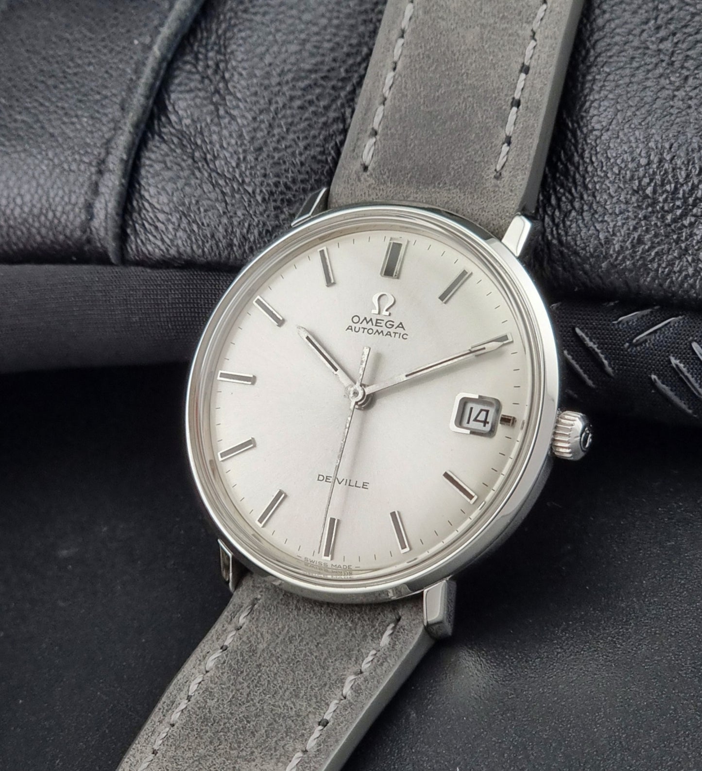 Omega DeVille watch with gray leather strap on a dark textured background
