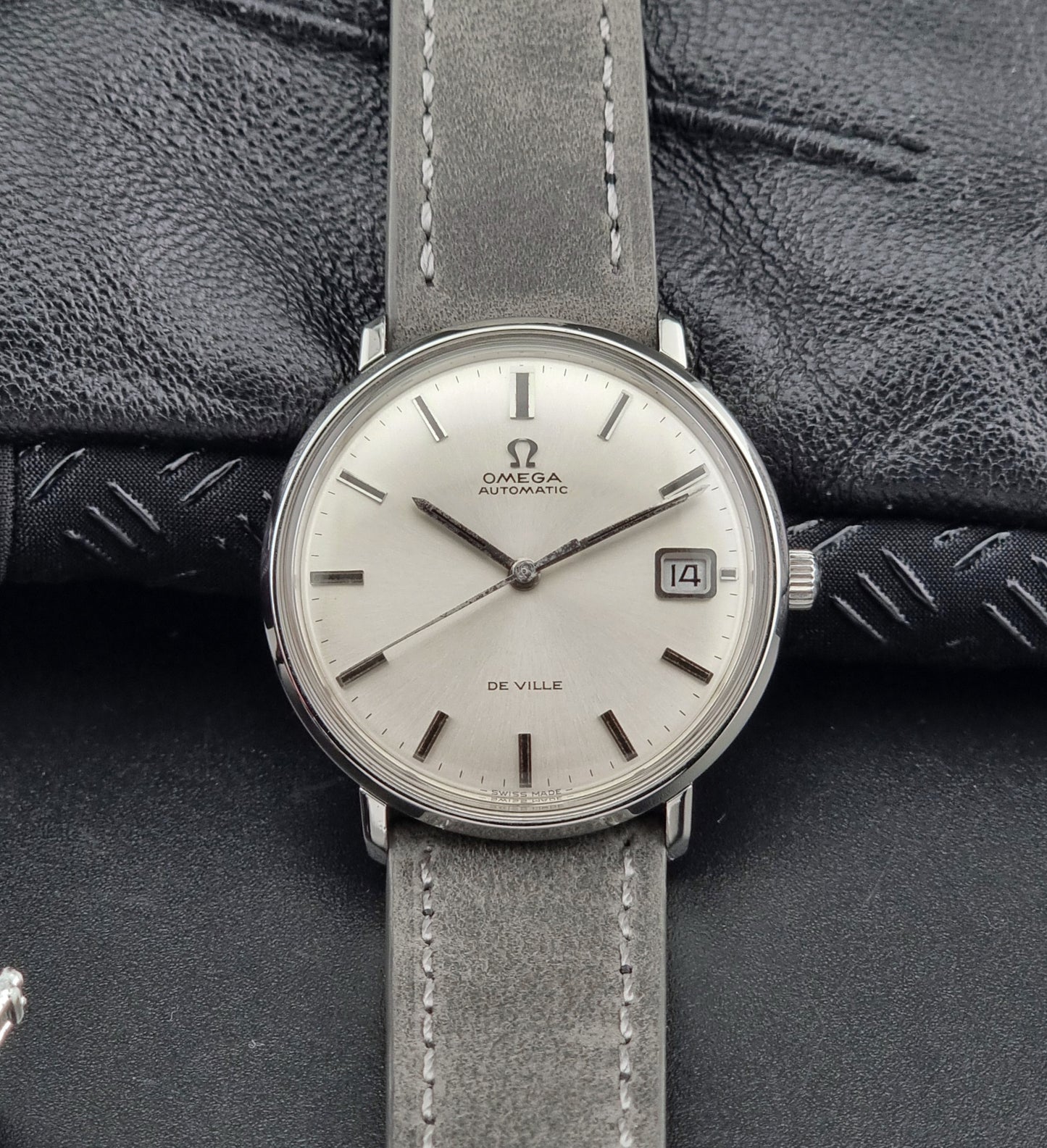 Omega watch with gray strap on a textured black background