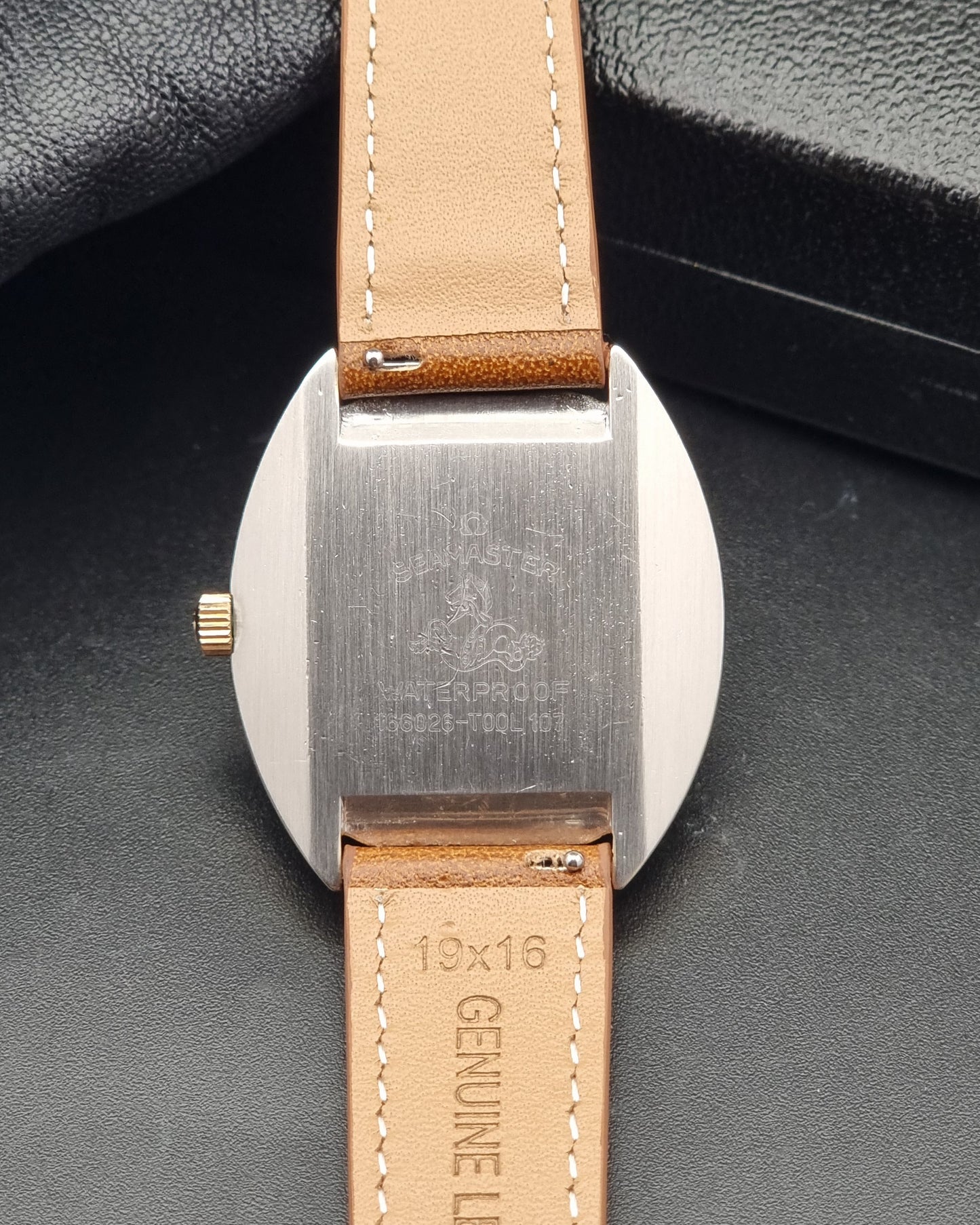 A Vintage Omega 166.026 Seamaster Cosmic Automatic Gold Capped watch on a dark background Close-up of the back of a wristwatch with a brushed stainless steel case