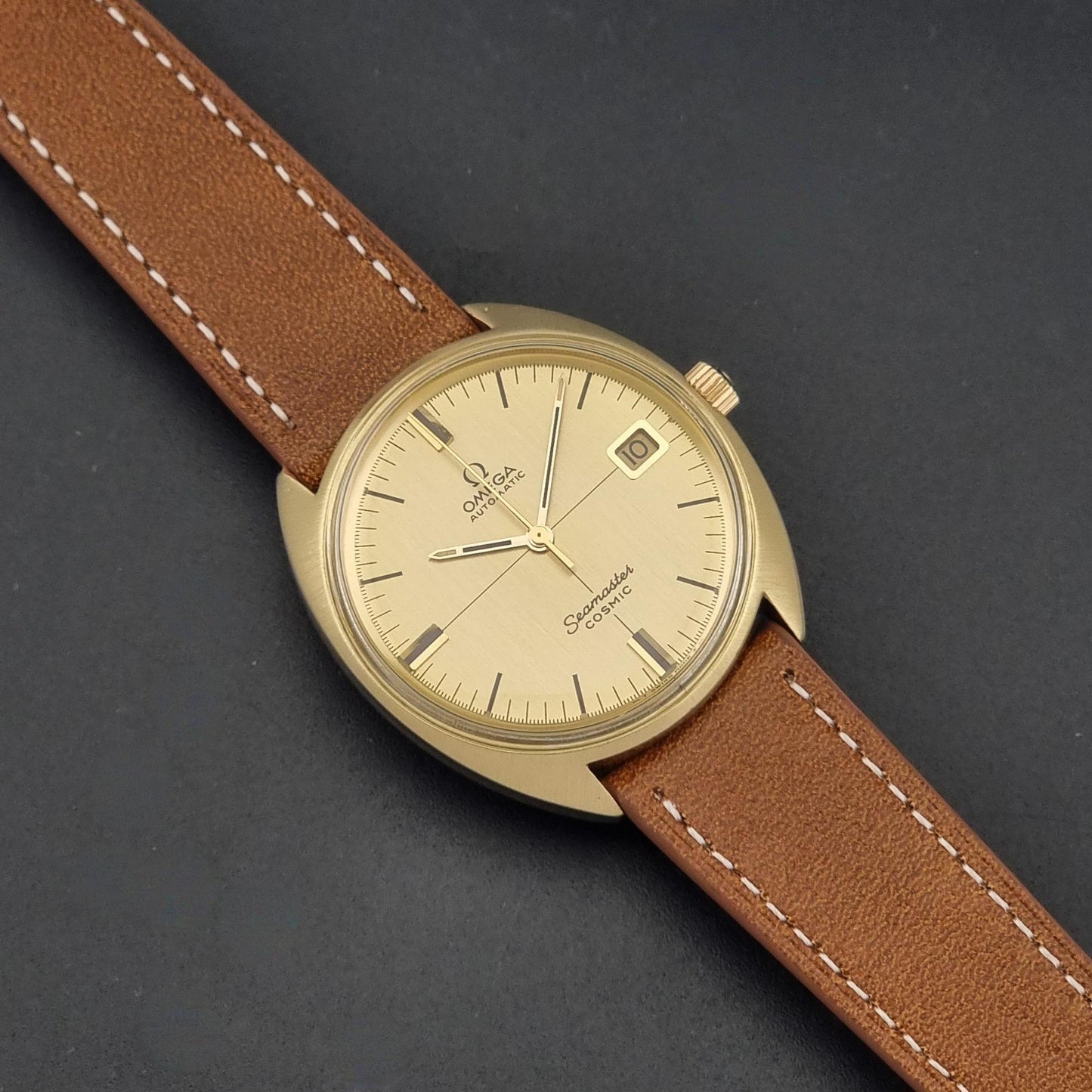 A Vintage Omega 166.026 Seamaster Cosmic Automatic Gold Capped watch on a dark background angled view