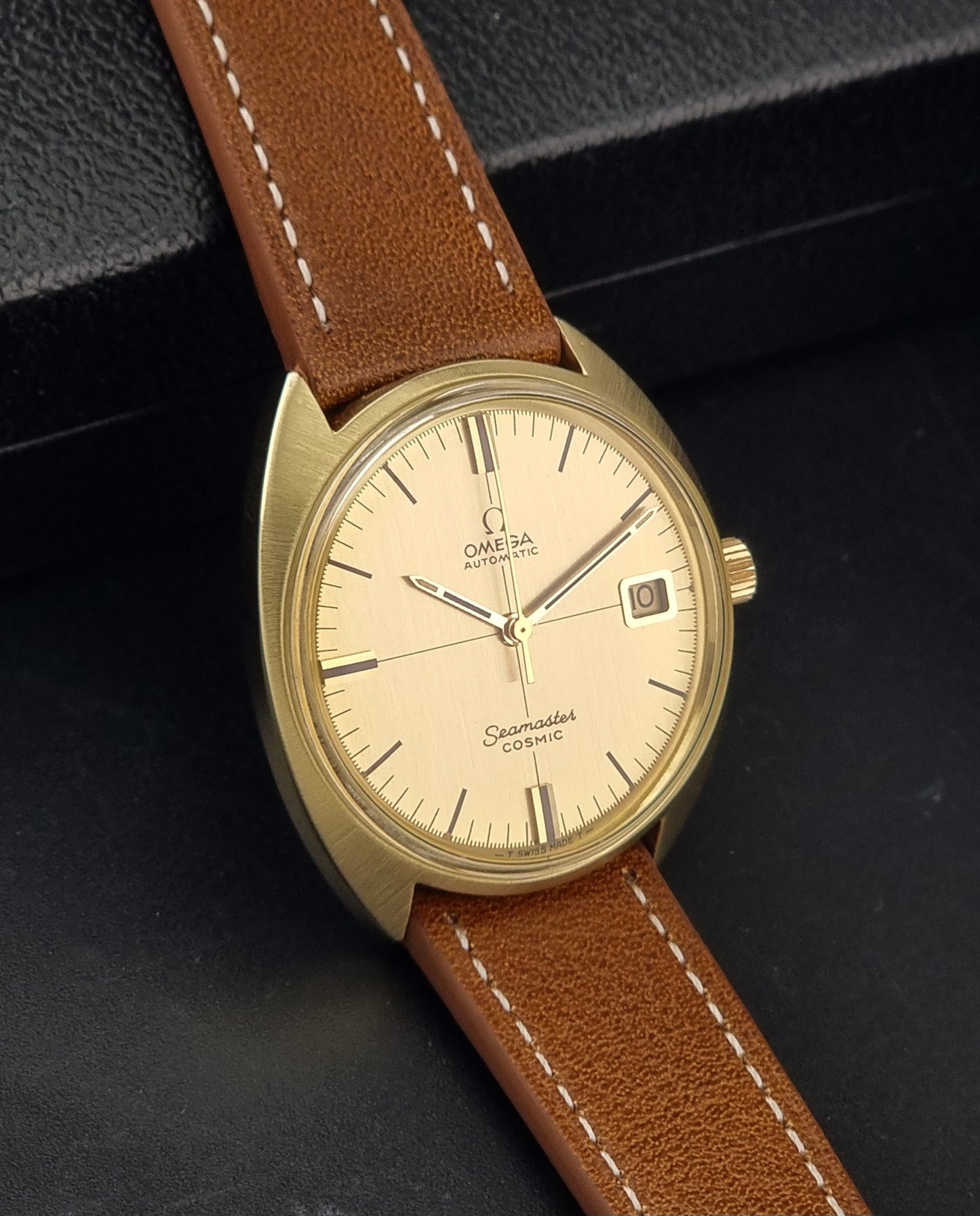 A Vintage Omega 166.026 Seamaster Cosmic Automatic Gold Capped watch on a dark background side view