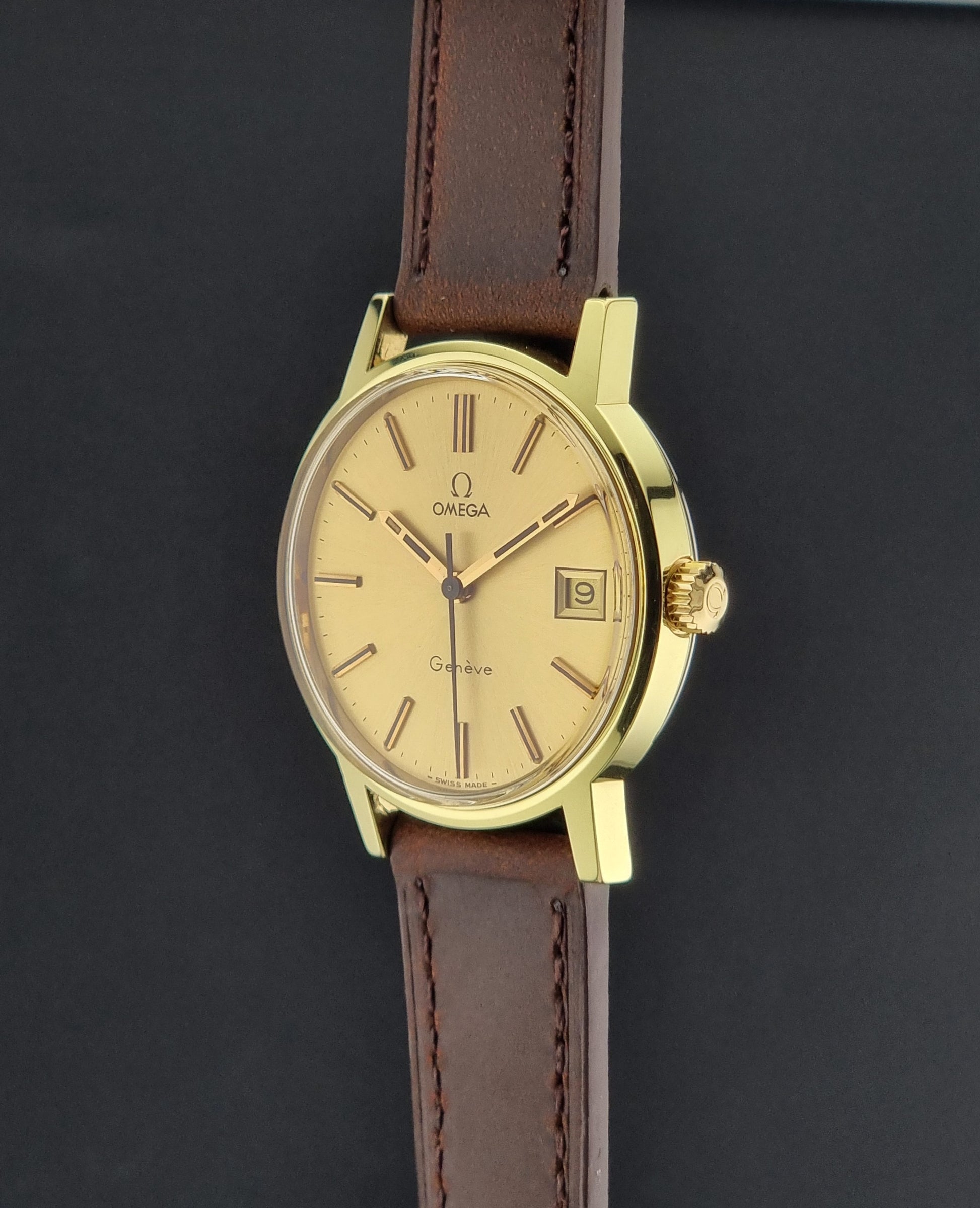 Vintage Gold Omega Geneve with a brown leather strap on a dark background