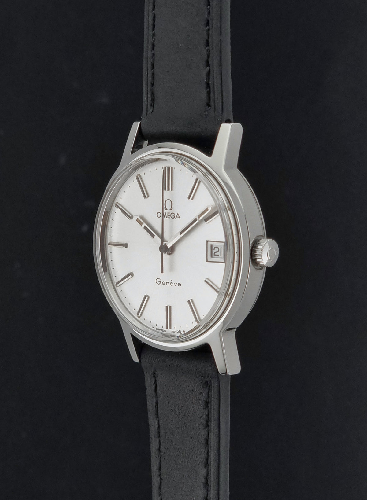 A Vintage Omega Geneve 136.0098 watch, white dial, and black leather strap shown against a dark background.