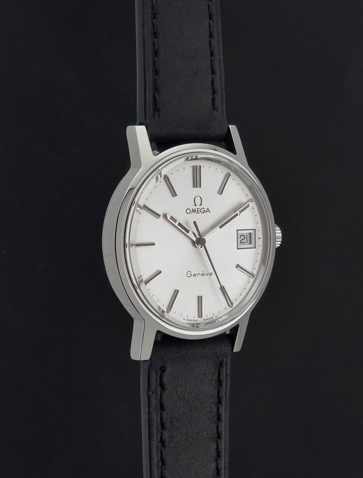 A Vintage Omega Geneve 136.0098 watch, white dial, and black leather strap shown against a dark background.