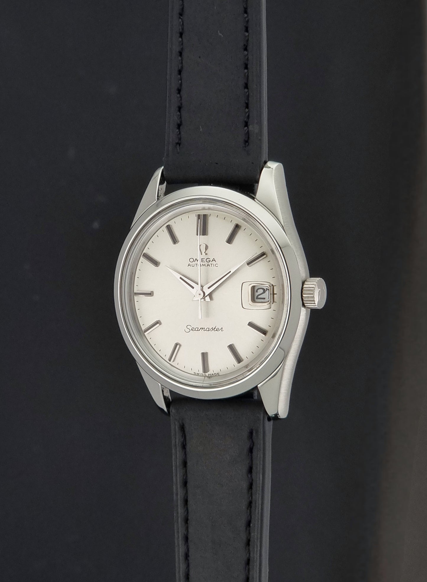 A Vintage Omega Seamaster 166.010 Wristwatch on a black leather strap on a dark background