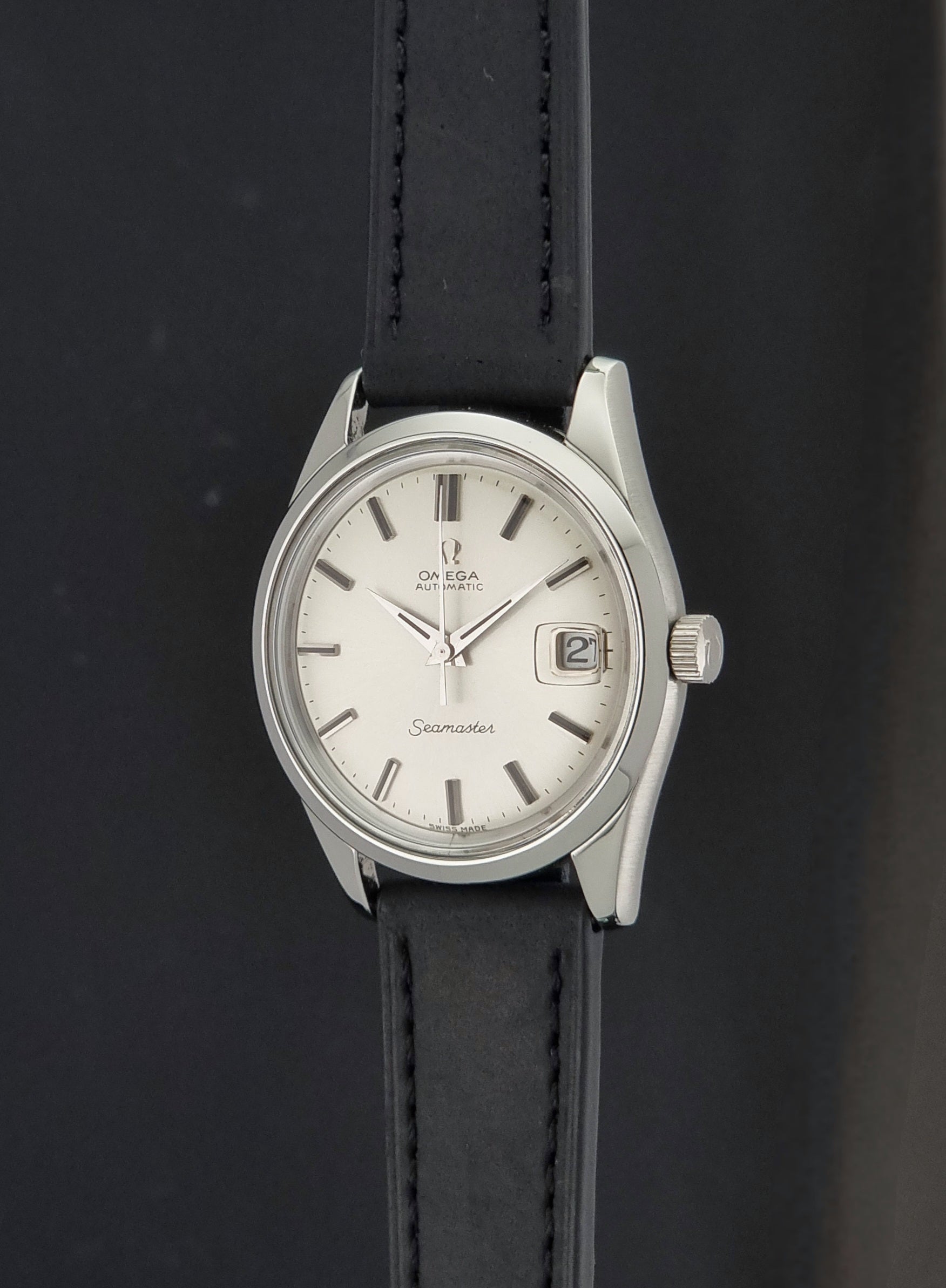 A Vintage Omega Seamaster 166.010 Wristwatch on a black leather strap on a dark background