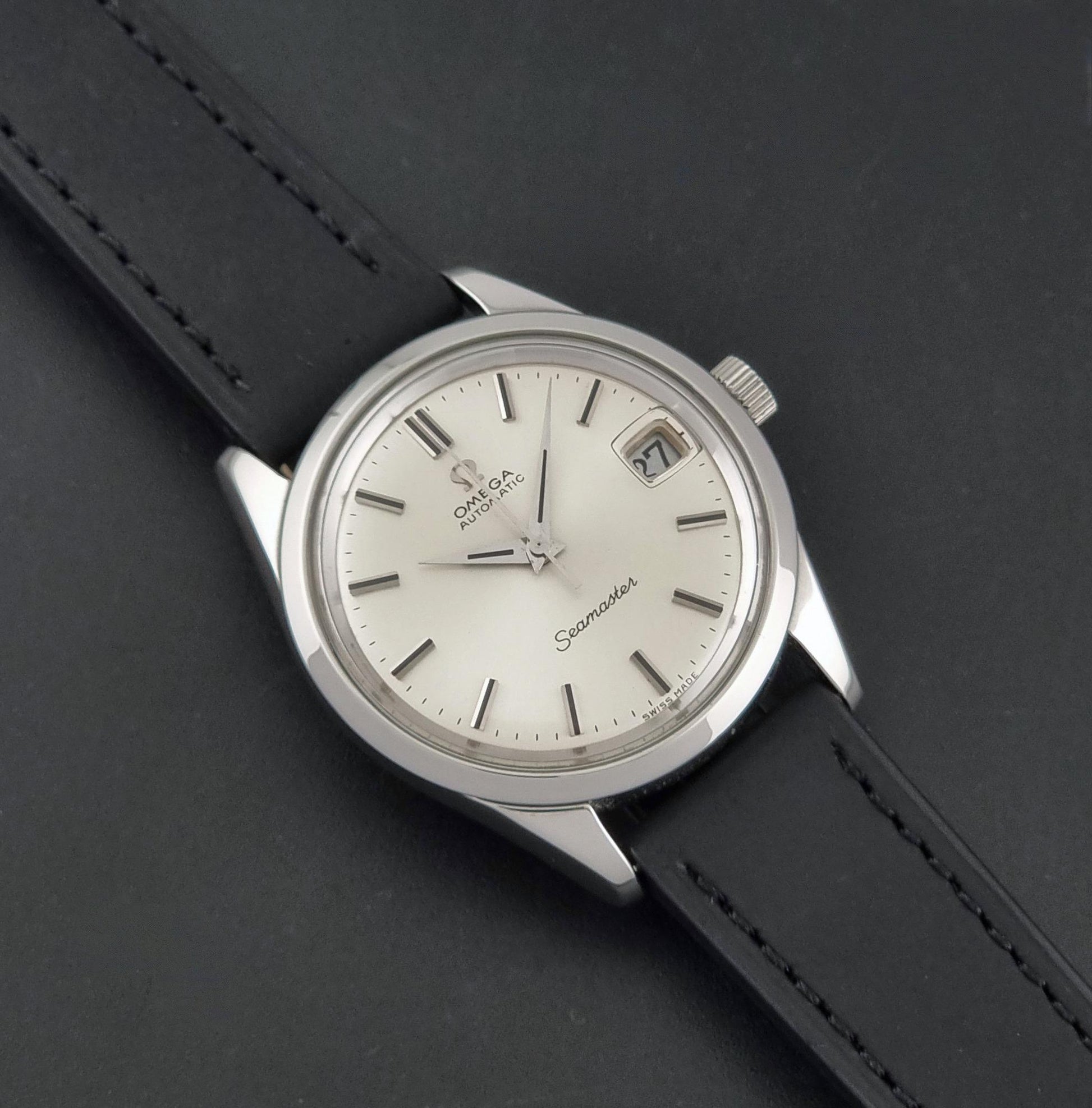A Vintage Omega Seamaster 166.010 Wristwatch at a 45 degree angle on a dark background