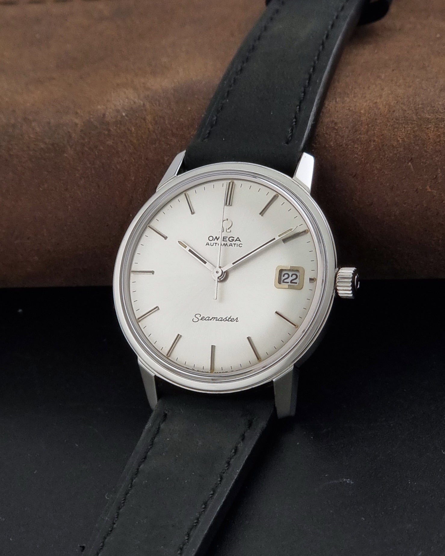 A Vintage Omega Seamaster watch 166.037 wristwatch , resting on a brown watch roll