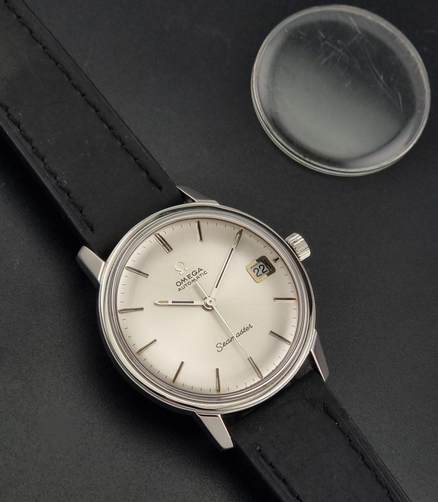 A Vintage Omega Seamaster watch 166.037 wristwatch  with a spare original crystal on a dark background