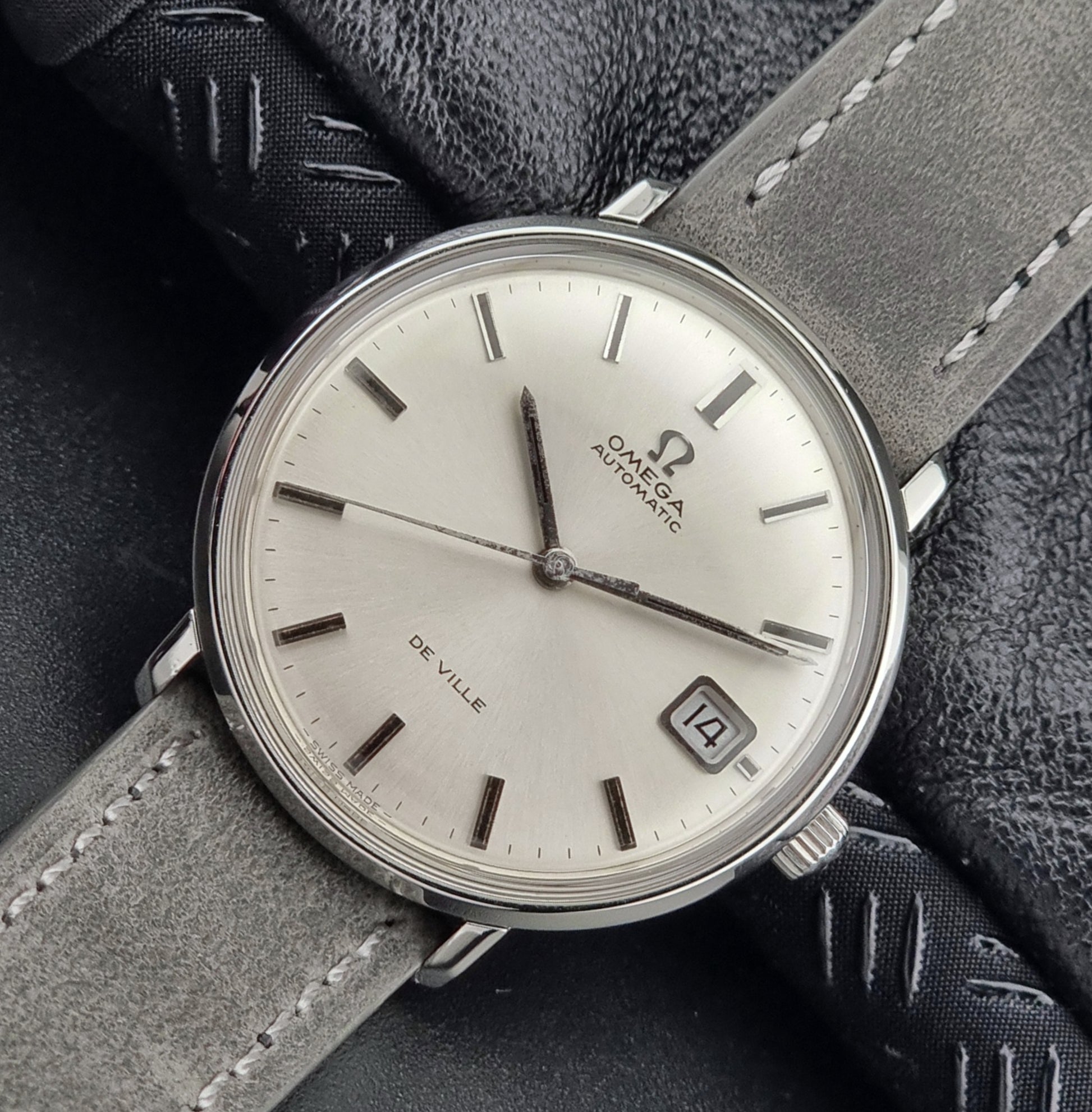 Vintage Omega watch with gray strap on a textured surface