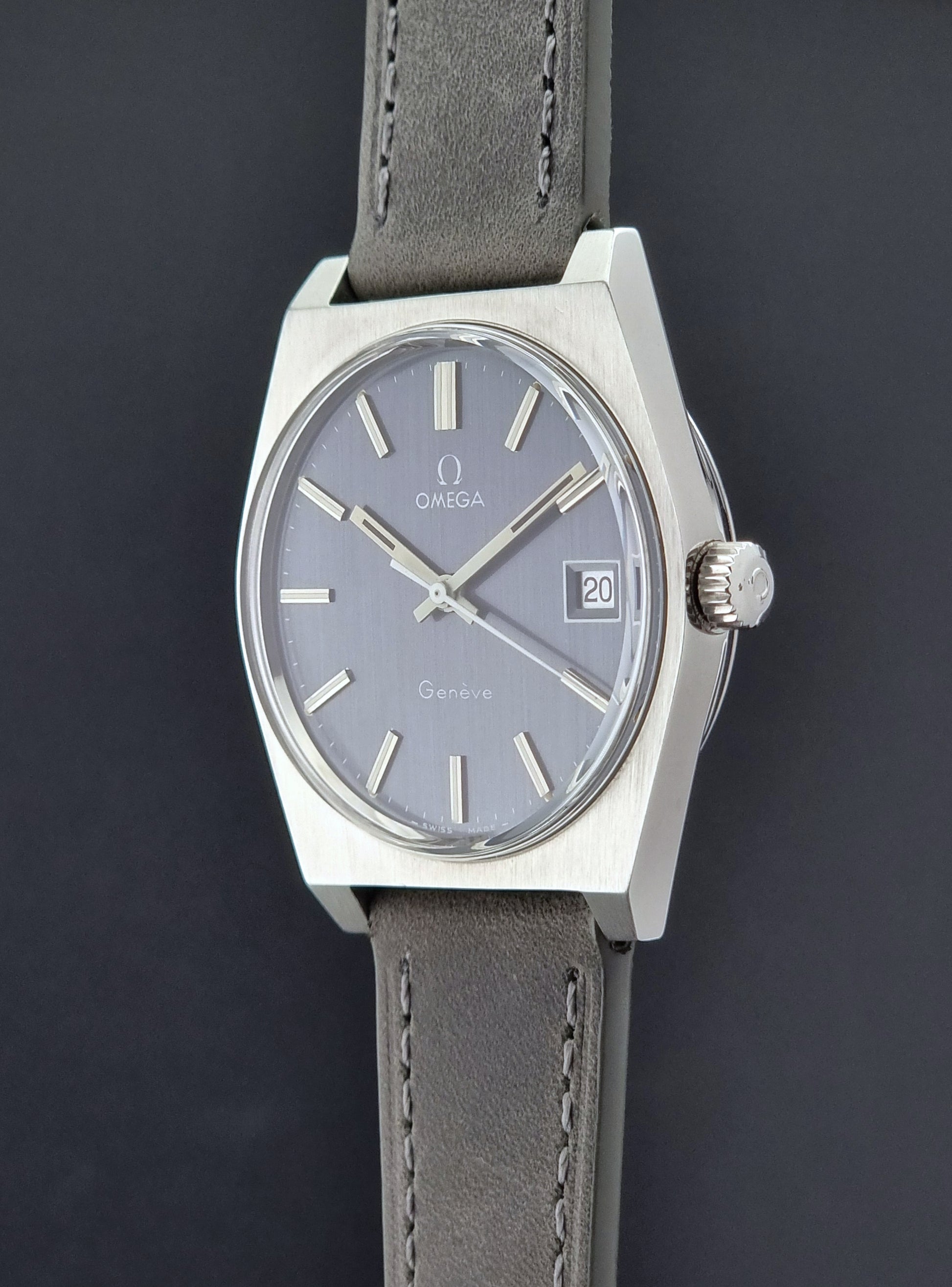 Vintage Omega Geneve watch with gray leather strap on a dark background