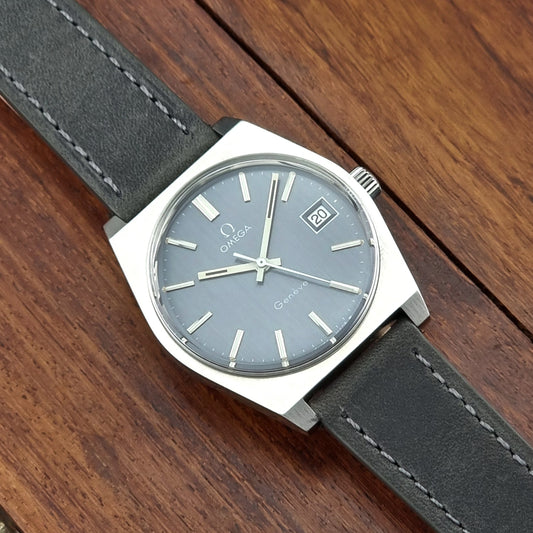 Vintage Omega Geneve watch with a black strap on a wooden surface