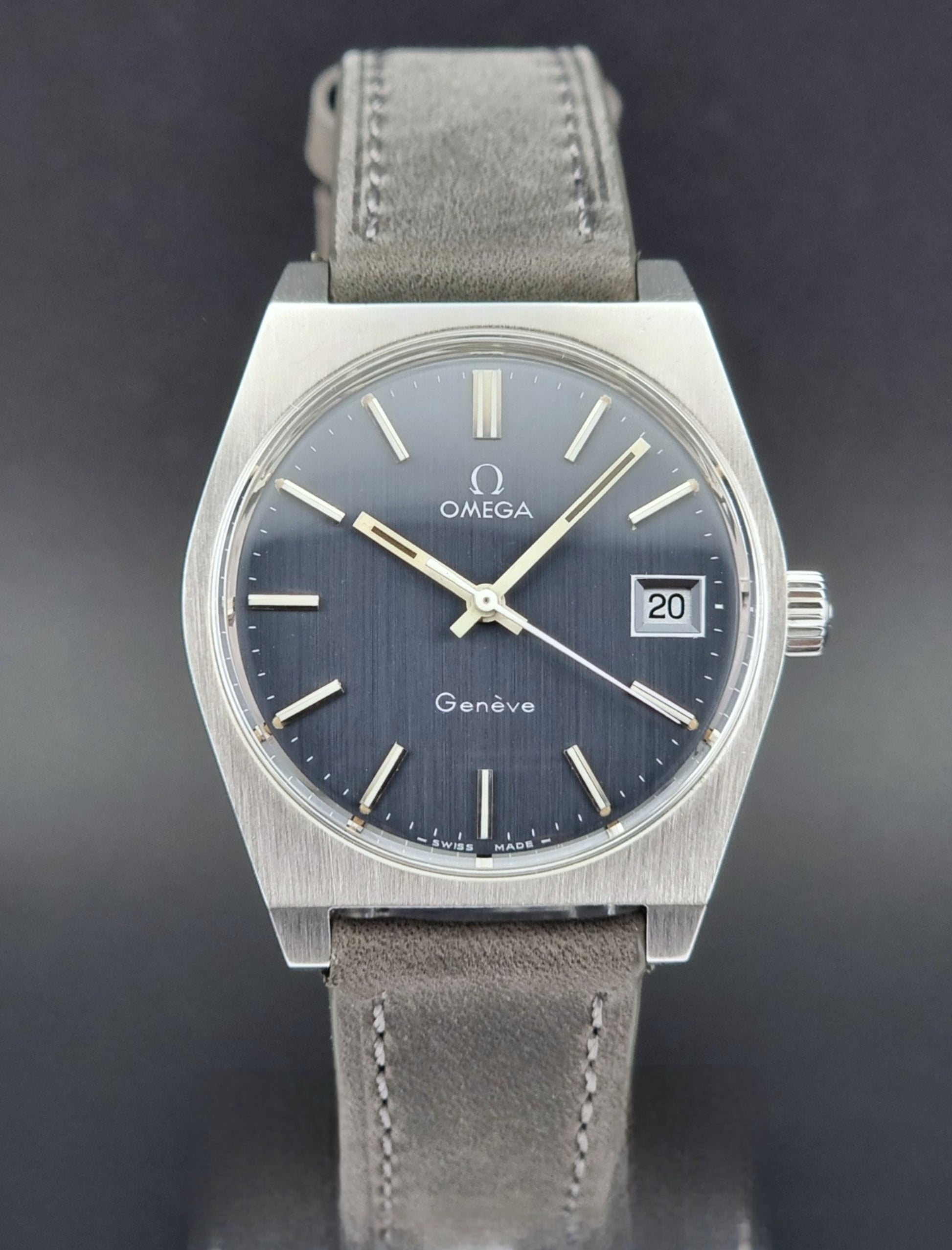 Vintage Omega Geneve watch with a gray strap on a dark background