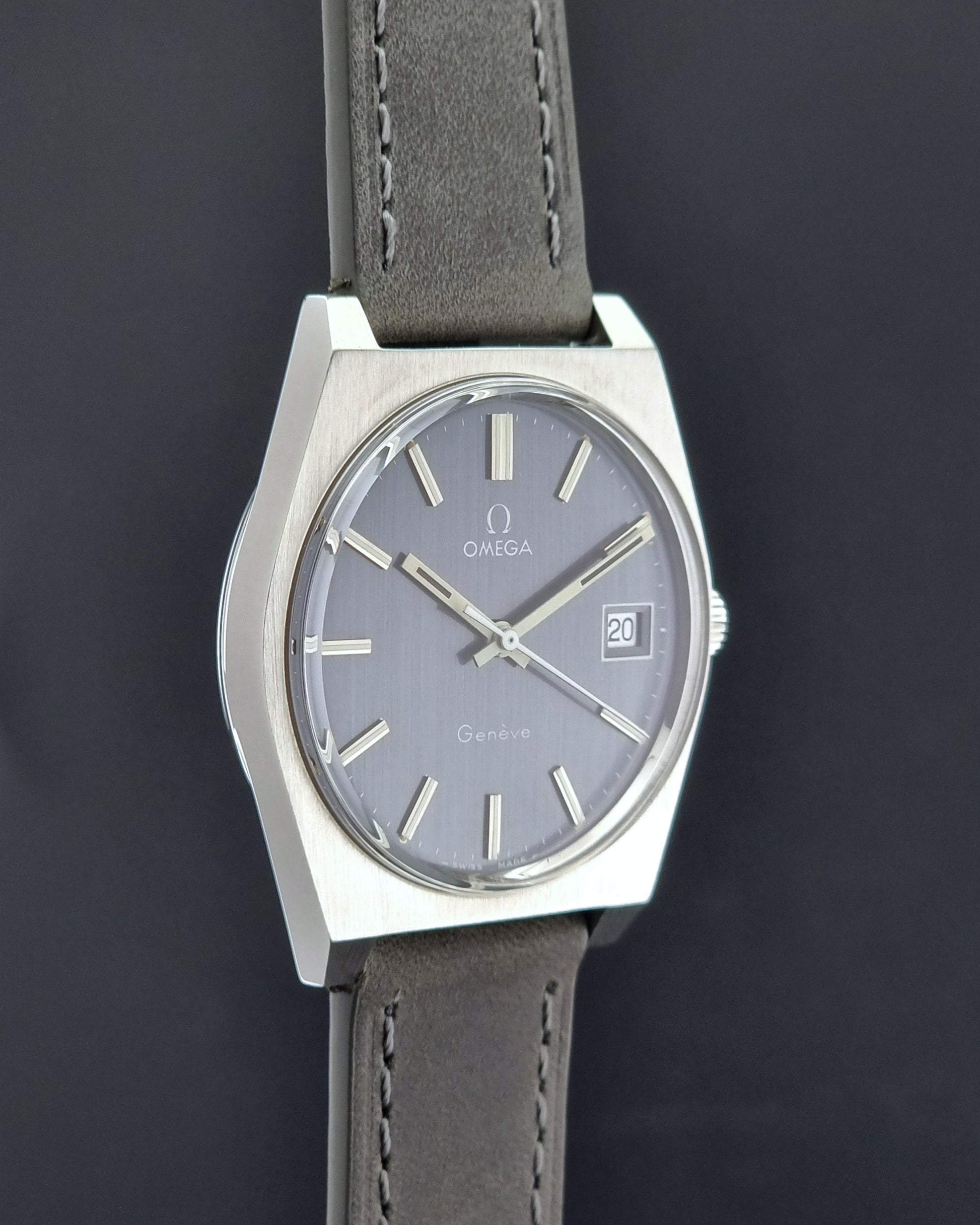 Vintage Omega Geneve watch with gray dial and leather strap on a dark background