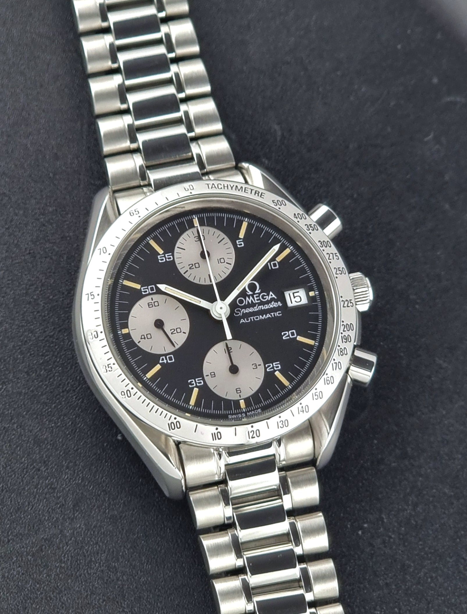 Vintage Omega Speedmaster watch 3511.50  Reverse Panda Date Chronograph with a black face on a dark background front close up