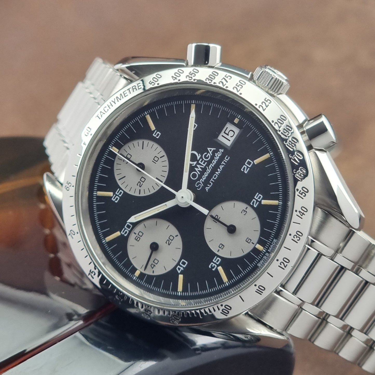 Vintage Omega Speedmaster watch 3511.50  Reverse Panda Date Chronograph with a black face on a dark background on its side close up