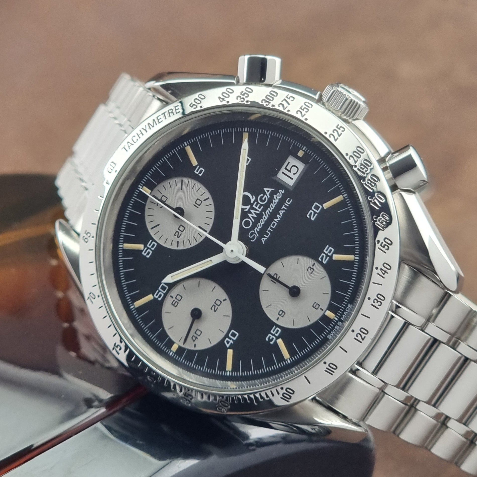 Vintage Omega Speedmaster watch 3511.50  Reverse Panda Date Chronograph with a black face on a dark background on its side close up