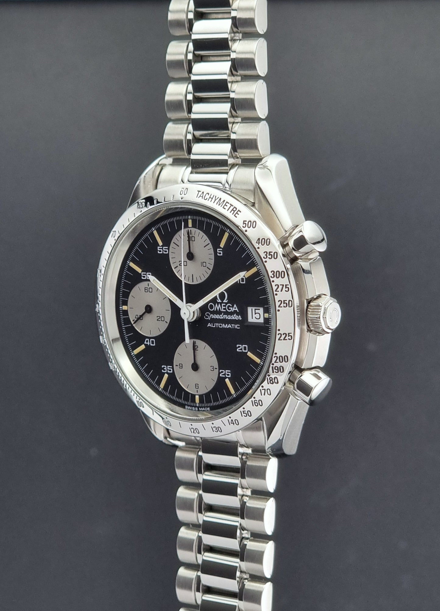 Vintage Omega Speedmaster watch 3511.50  Reverse Panda Date Chronograph with a black face on a dark background crown profile