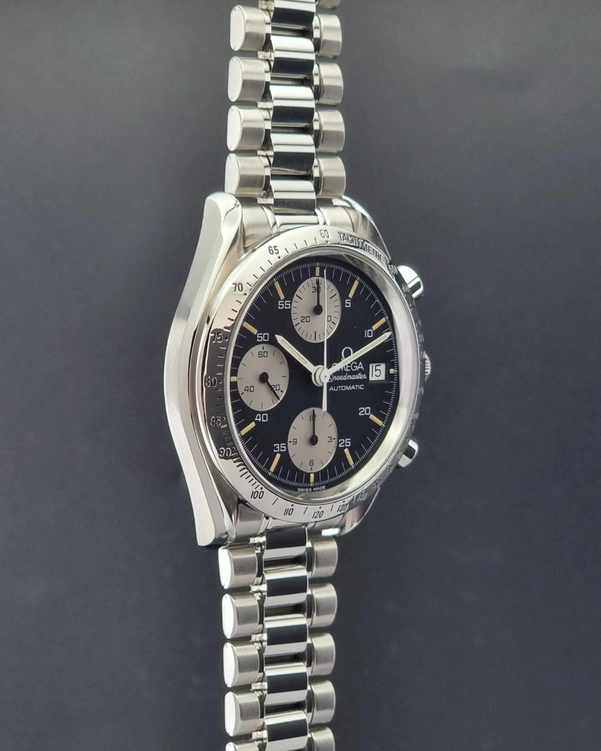 Vintage Omega Speedmaster watch 3511.50  Reverse Panda Date Chronograph with a black face on a dark background side profile