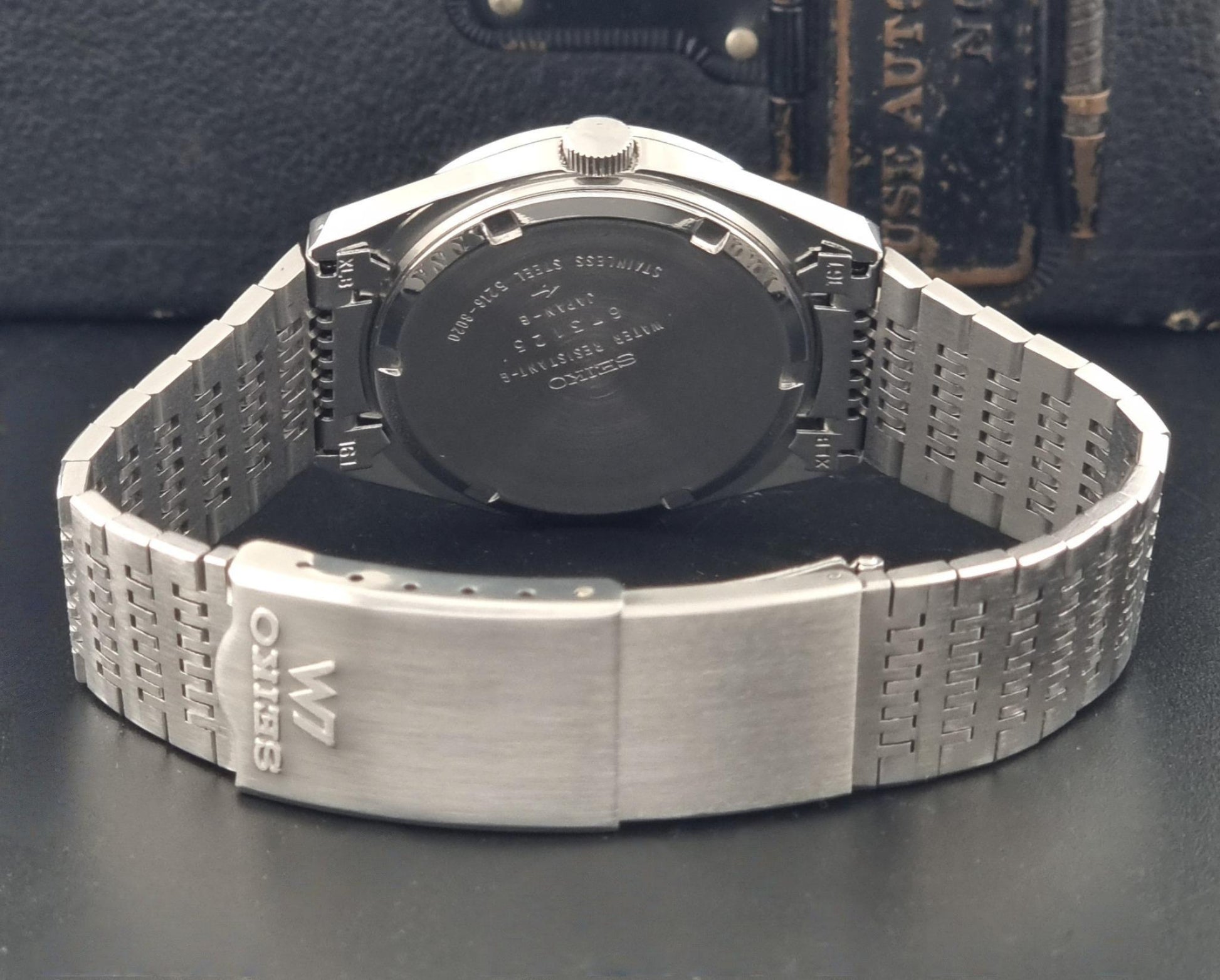 A close-up shot of the back of a Vintage Seiko LordMatic Special 5216-8020 Wristwatch with a metal bracelet, showing the case back and clasp