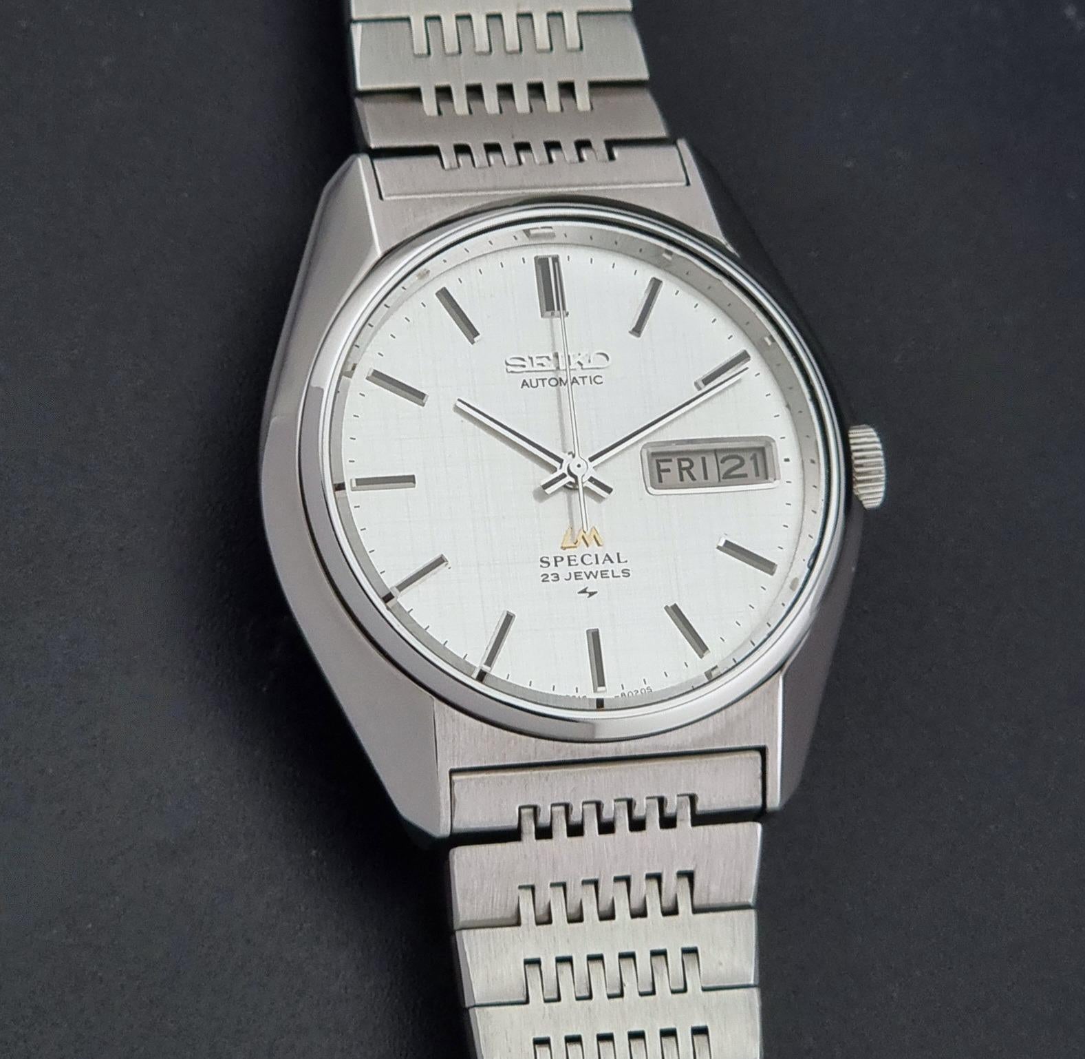 A Vintage Seiko LordMatic Special 5216-8020 Wristwatch photographed on a dark textured background. The watch features a day-date window at 3 o'clock.