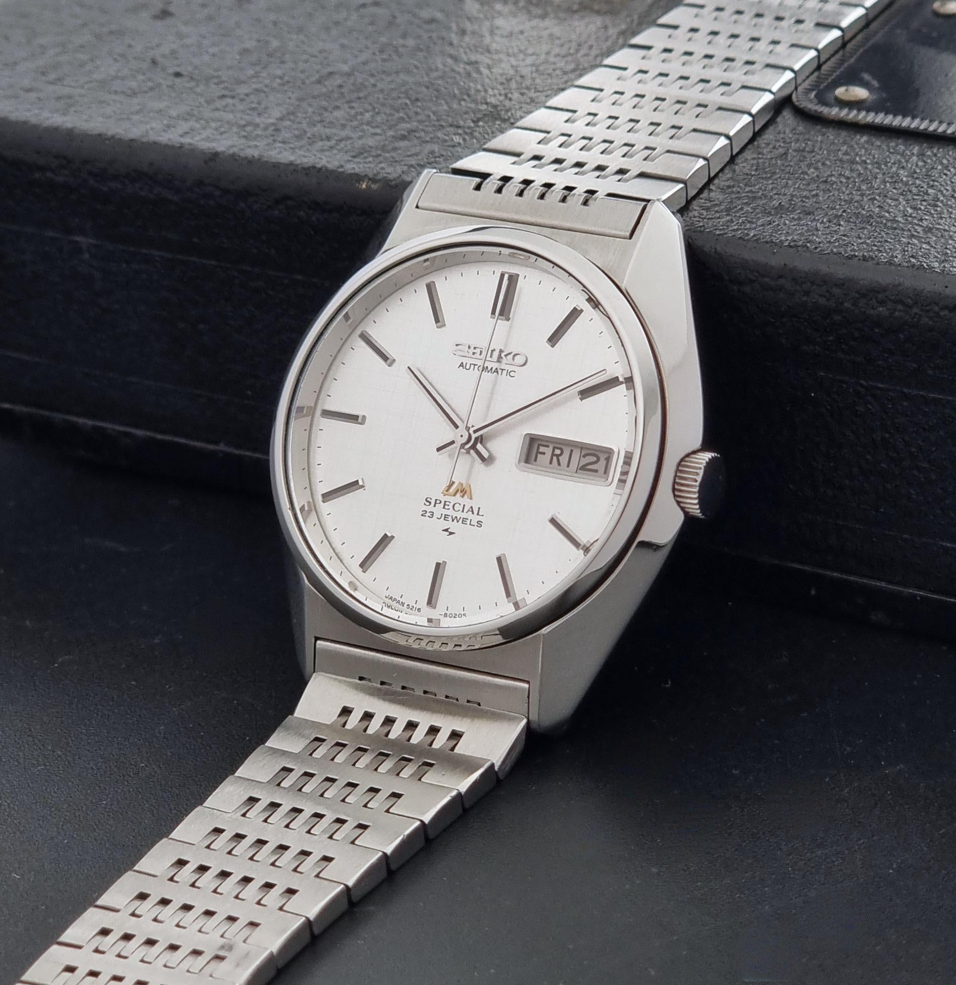 A Vintage Seiko LordMatic Special 5216-8020 Wristwatch with a silver stainless steel case and integrated metal link bracelet, featuring a white dial with a day-date window