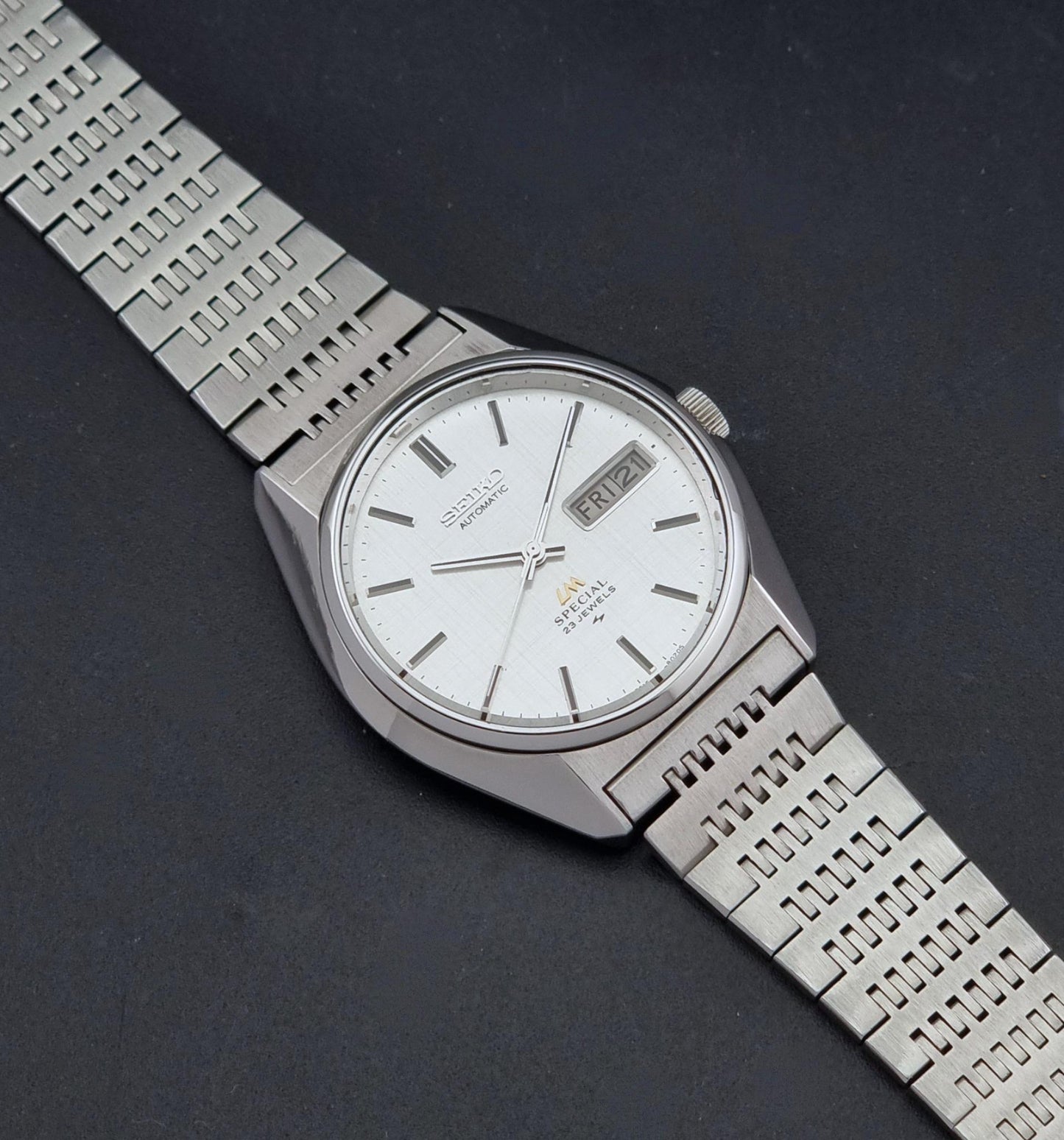 A Vintage Seiko LordMatic Special 5216-8020 Wristwatch, photographed diagonally on a dark textured background.