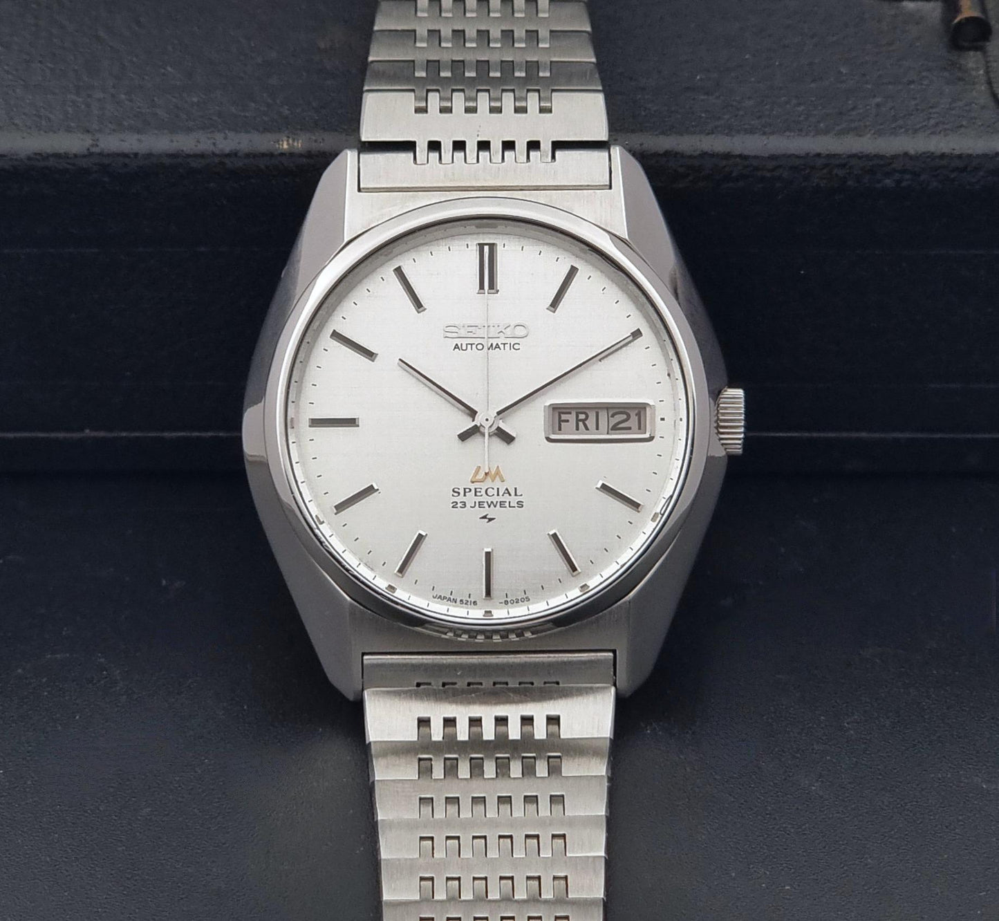 A Vintage Seiko LordMatic Special 5216-8020 automatic wristwatch with a silver-toned stainless steel case and link bracelet, featuring a white dial with a day-date window and silver hour markers.