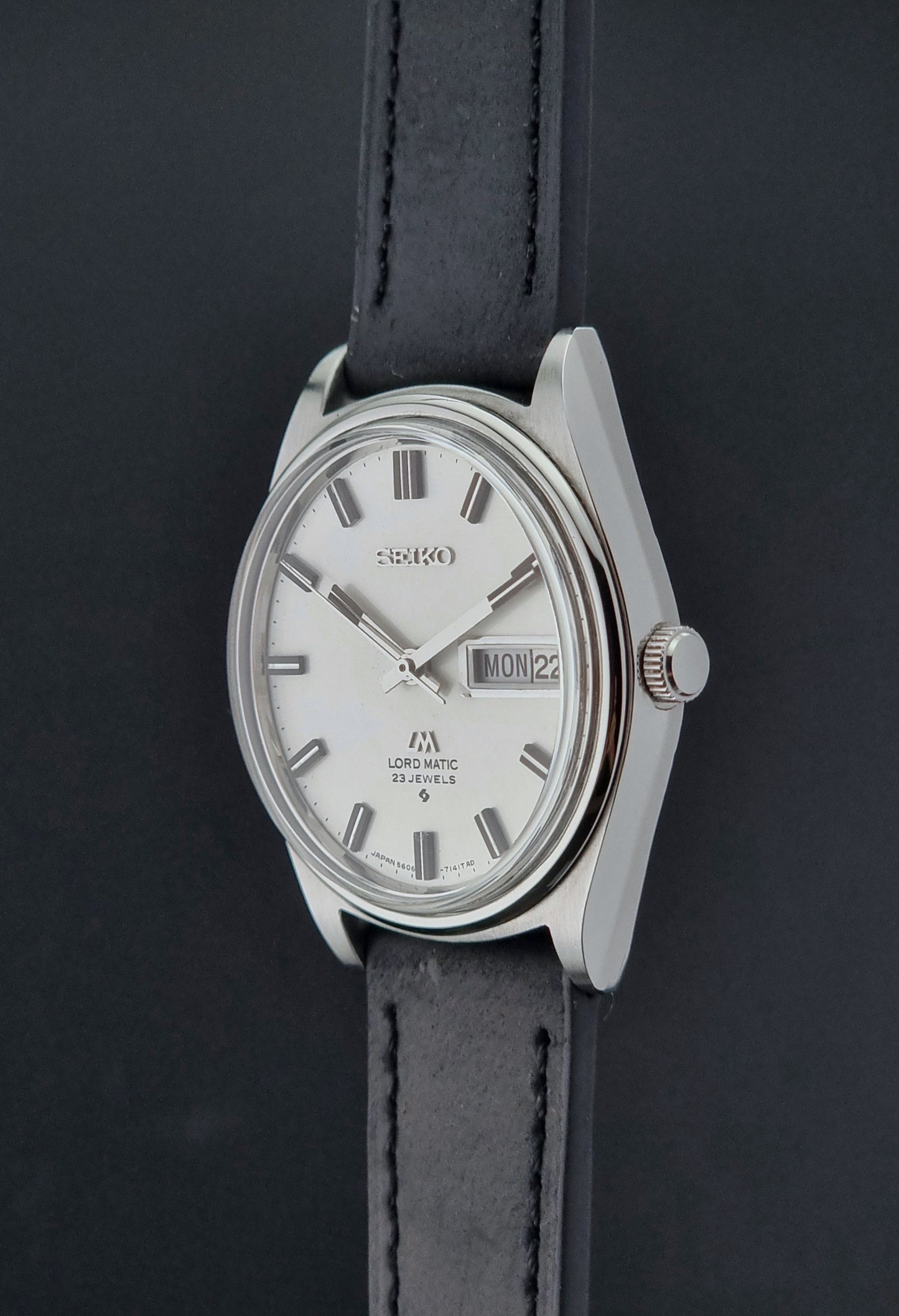 Vintage Seiko Lord Matic watch with a silver case and black leather strap on a dark background