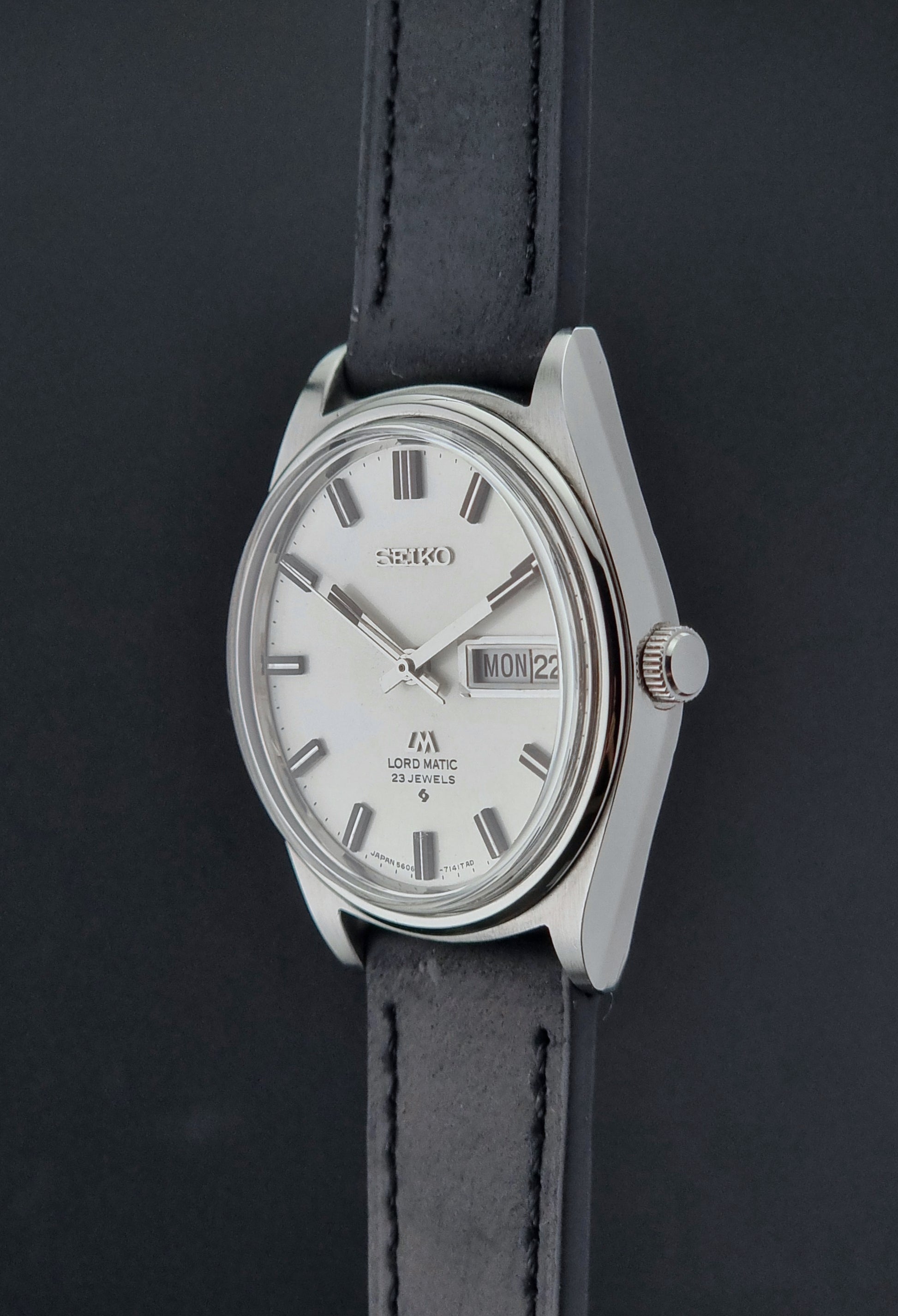 Vintage Seiko Lord Matic watch with a silver case and black leather strap on a dark background