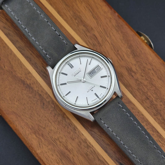 Vintage Seiko Lordmatic 5606-7071 Wristwatch with gray strap on a wooden surface