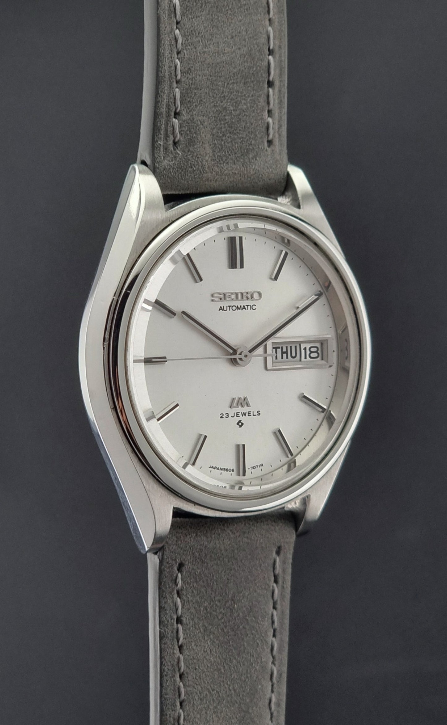 Vintage Seiko Lordmatic 5606-7071 Wristwatch with gray strap on a dark background