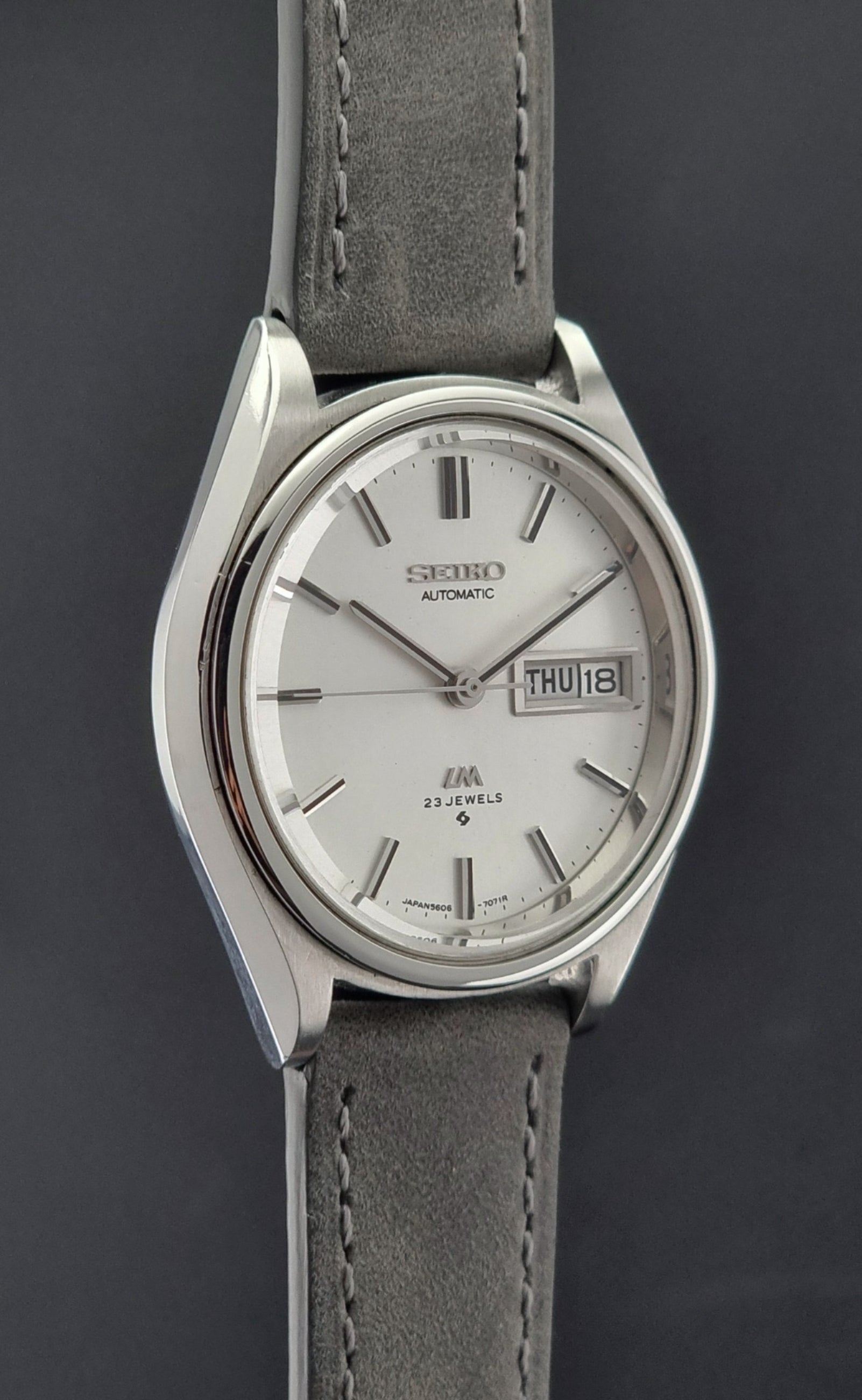 Vintage Seiko Lordmatic 5606-7071 Wristwatch with gray strap on a dark background