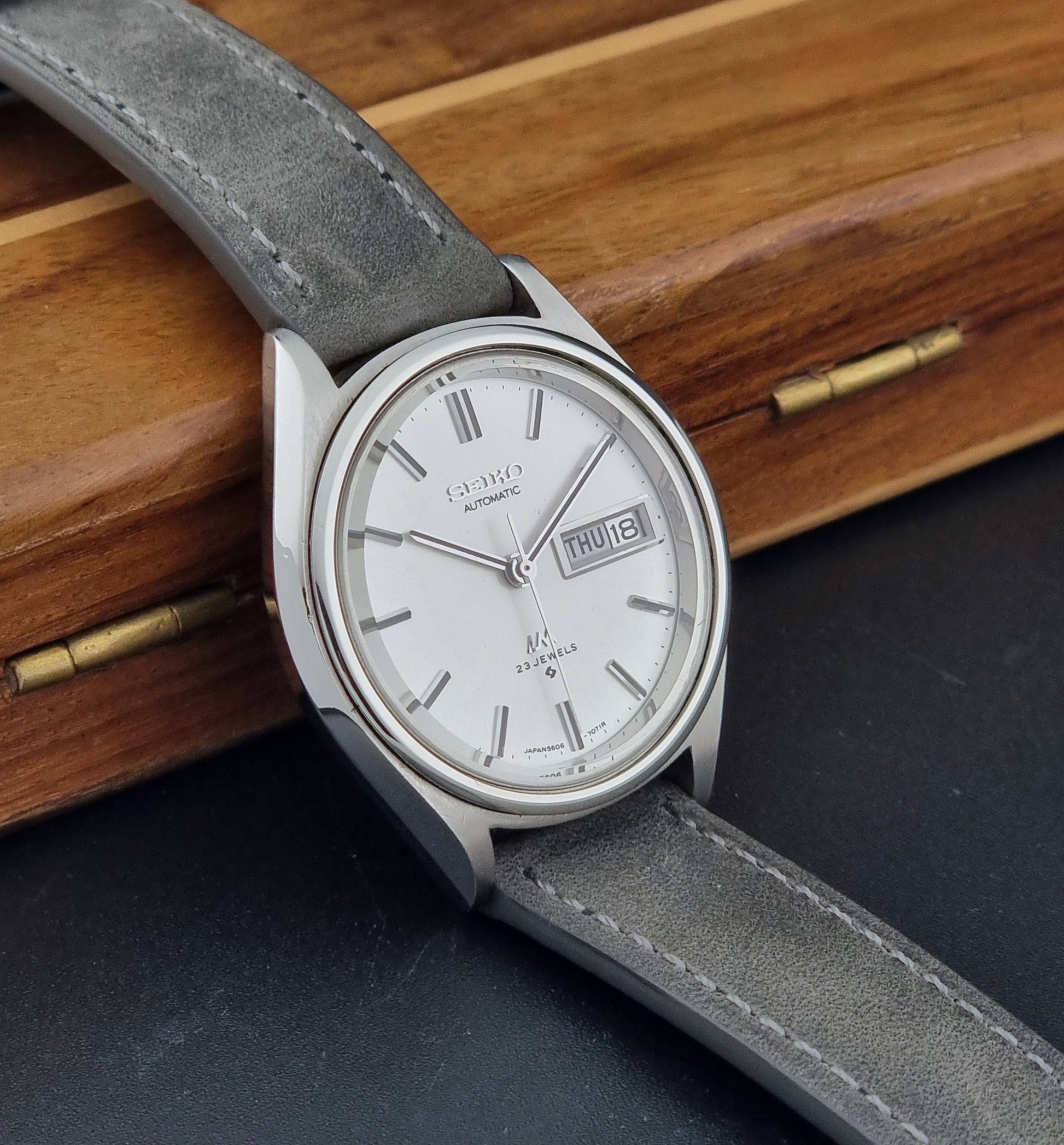 Vintage Seiko Lordmatic 5606-7071 Wristwatch with gray strap on a wooden surface