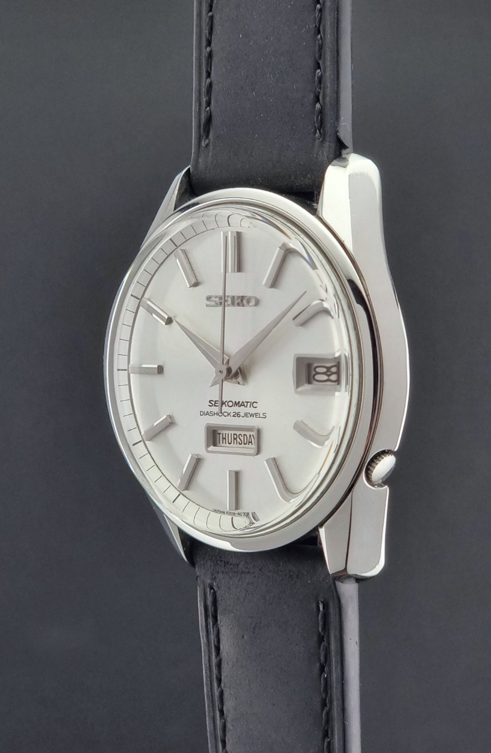 Seiko Seikomatic 6206-8040 Wristwatch with silver dial and black leather strap on a dark background