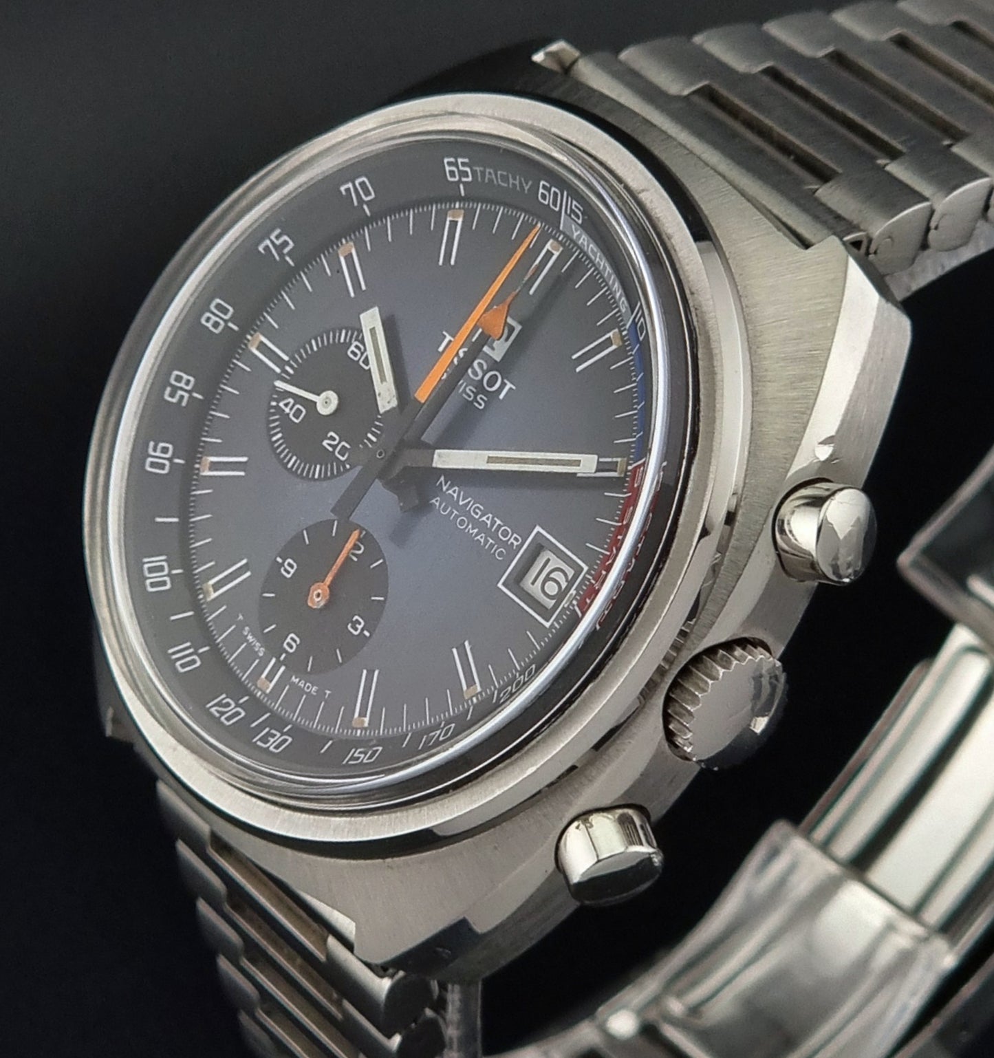 Close-up of a silver watch with a dark face on a black background