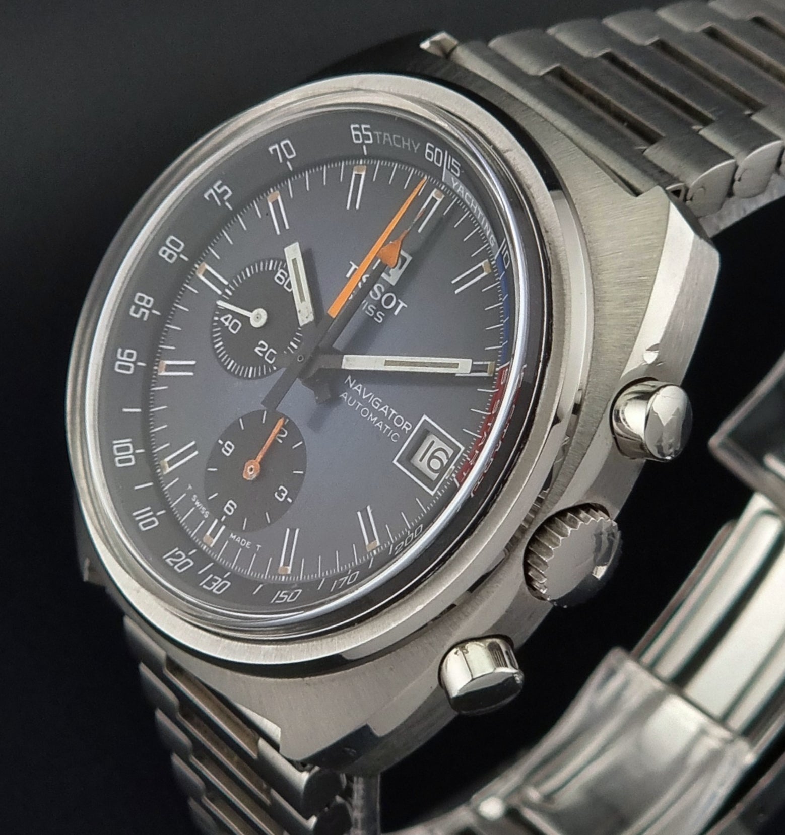 Close-up of a silver watch with a dark face on a black background