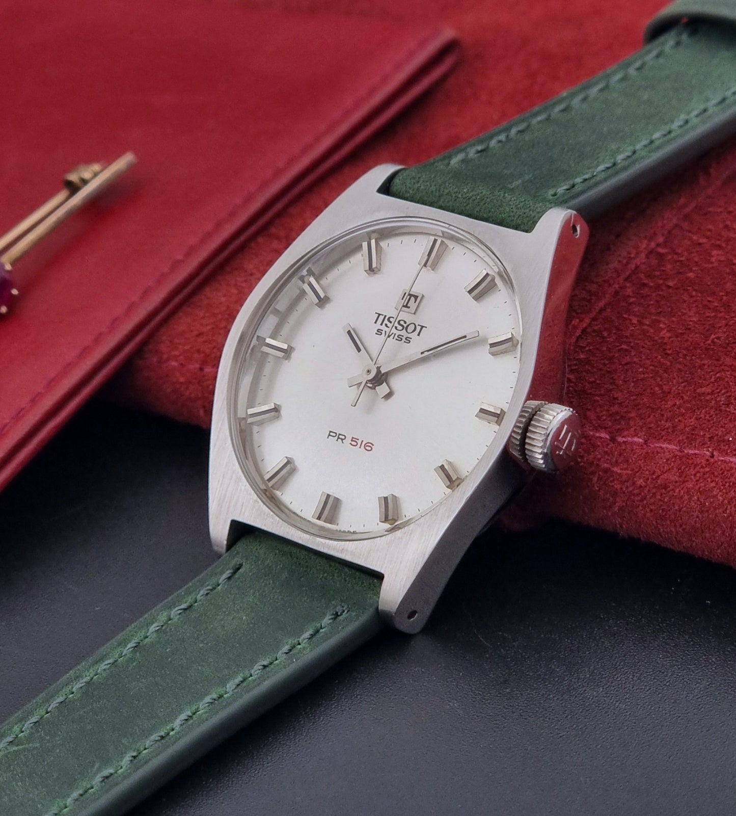 Vintage Tissot 41620 PR 516 wristwatch with green strap and silver case on a gray background crown view