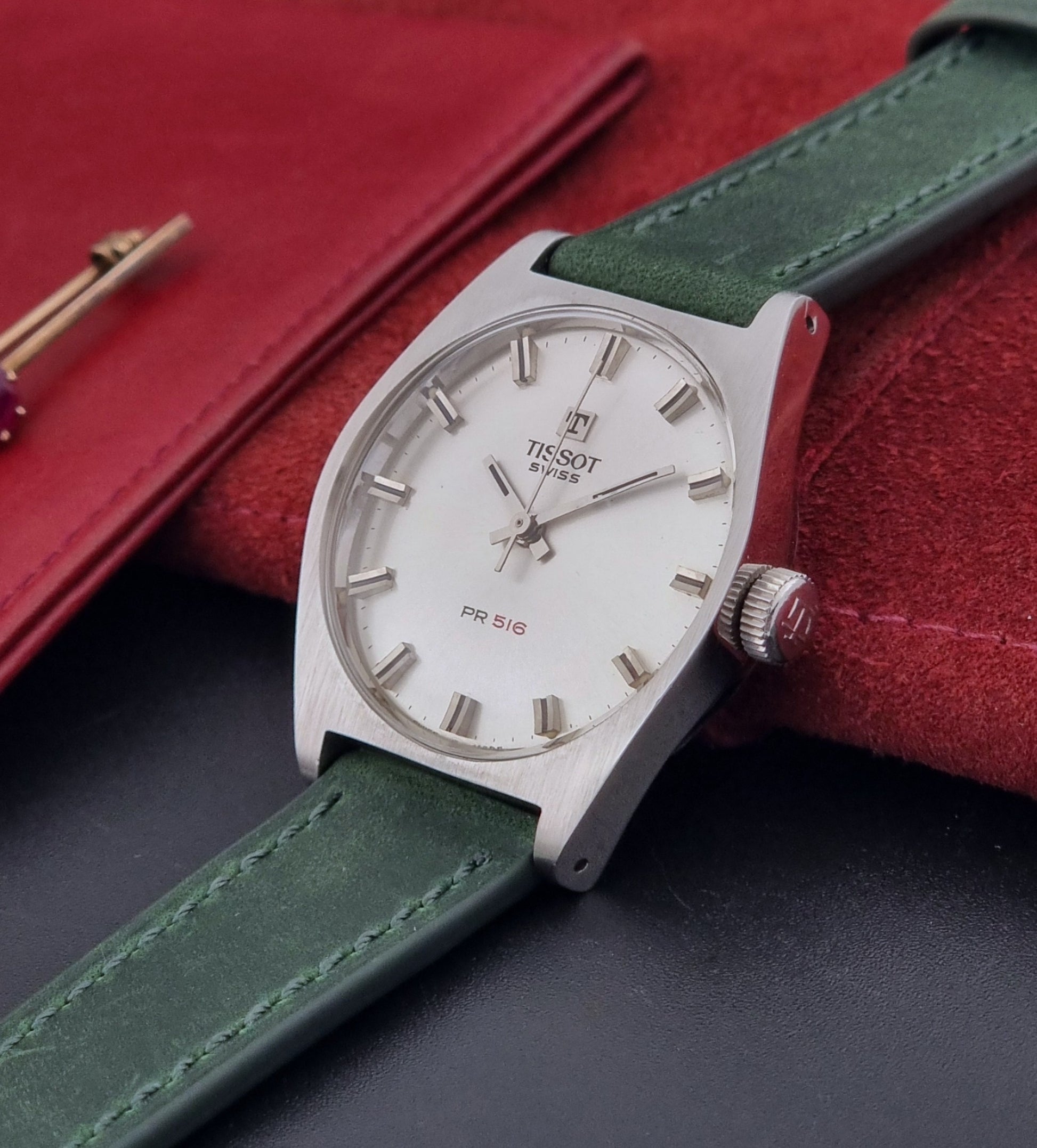 Vintage Tissot 41620 PR 516 wristwatch with green strap and silver case on a gray background crown view