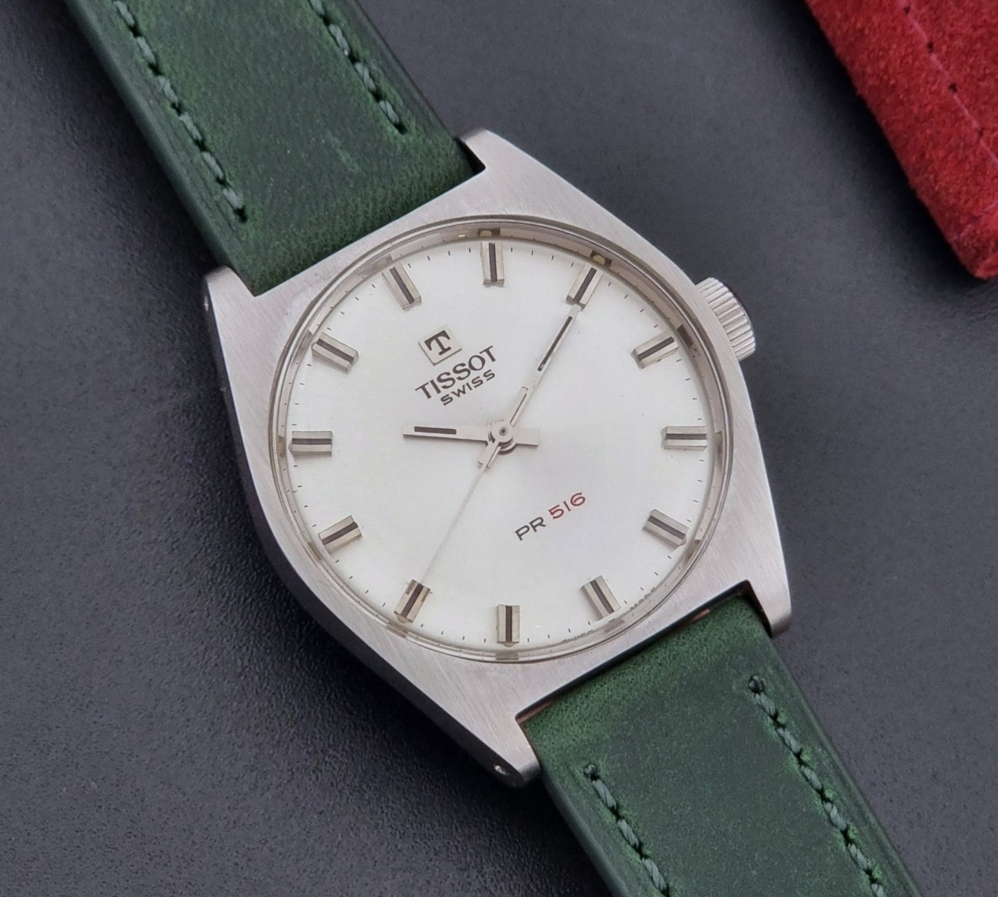 Vintage Tissot 41620 PR 516 wristwatch with green strap and silver case on a gray background dial view