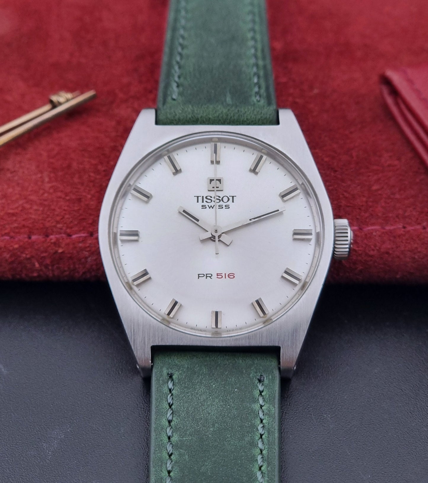 Vintage Tissot 41620 PR 516 wristwatch with green strap and silver case on a gray background front view