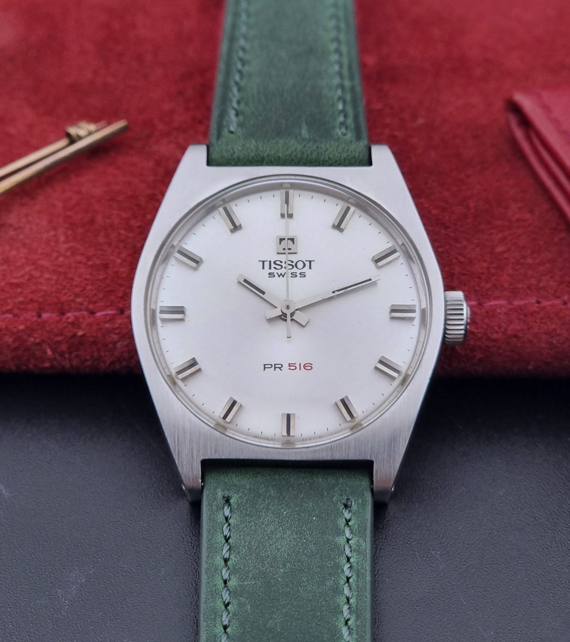 Vintage Tissot 41620 PR 516 wristwatch with green strap and silver case on a gray background front view