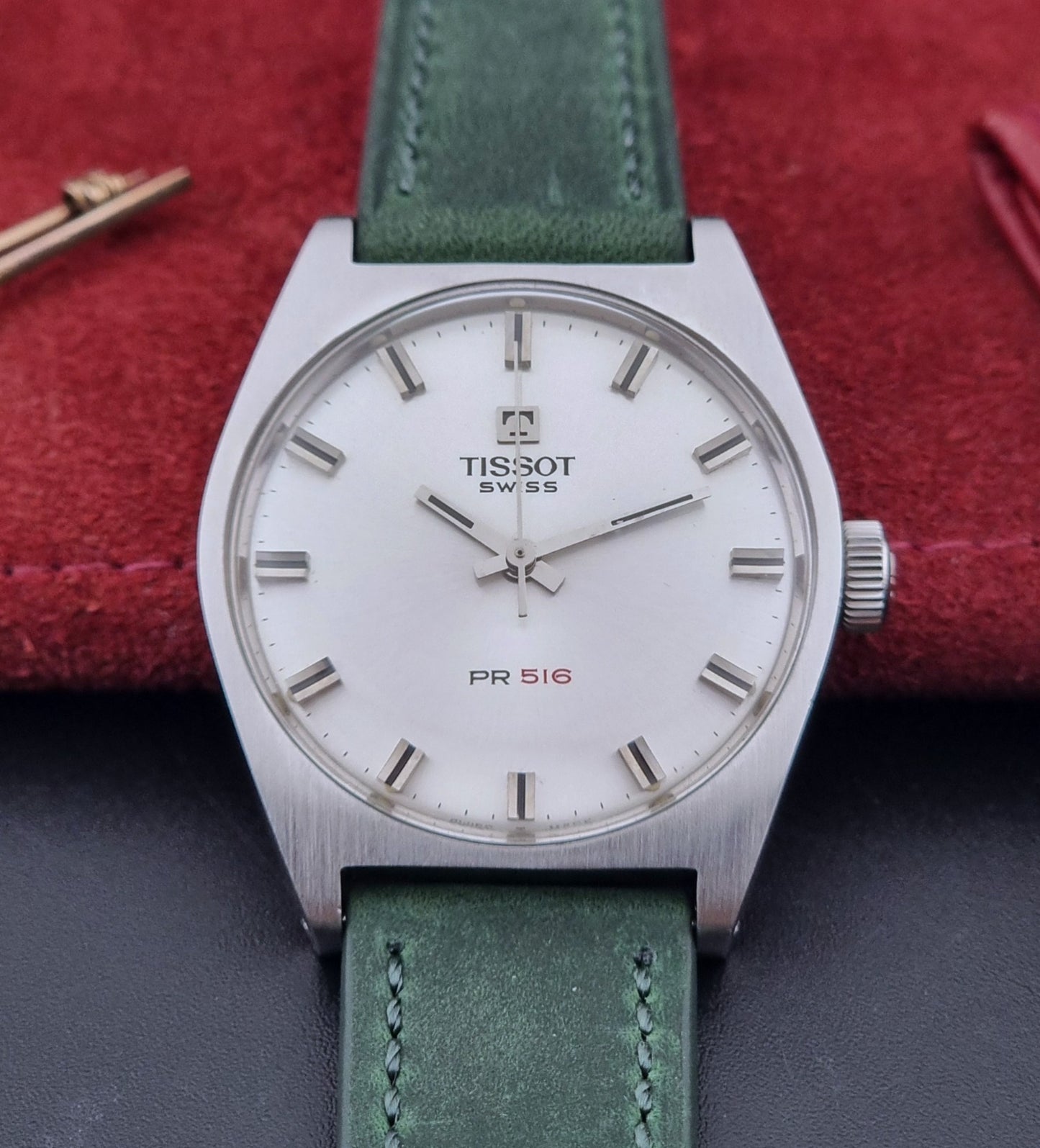 Vintage Tissot 41620 PR 516 wristwatch with green strap and silver case on a gray background close dial view