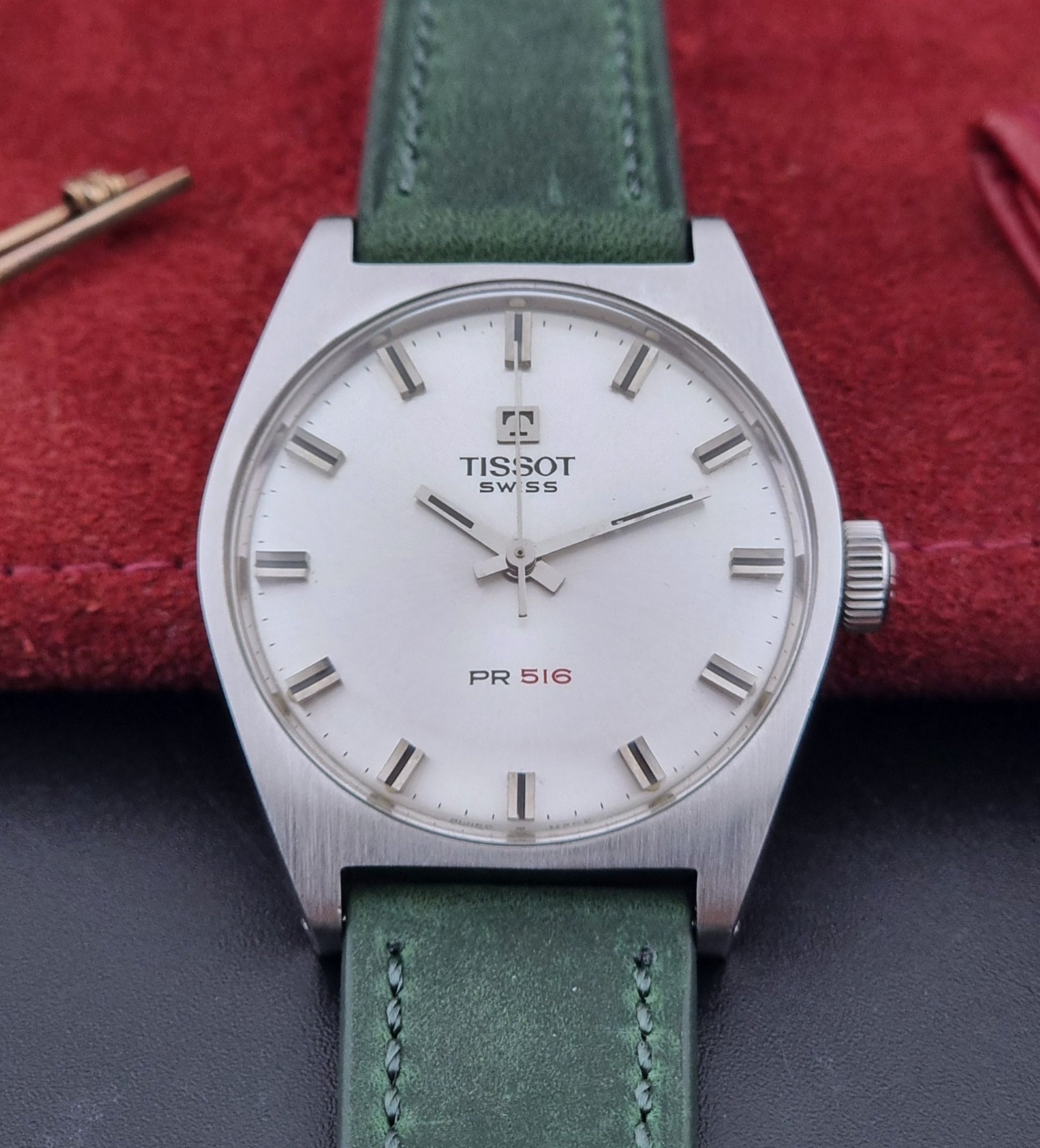 Vintage Tissot 41620 PR 516 wristwatch with green strap and silver case on a gray background close dial view