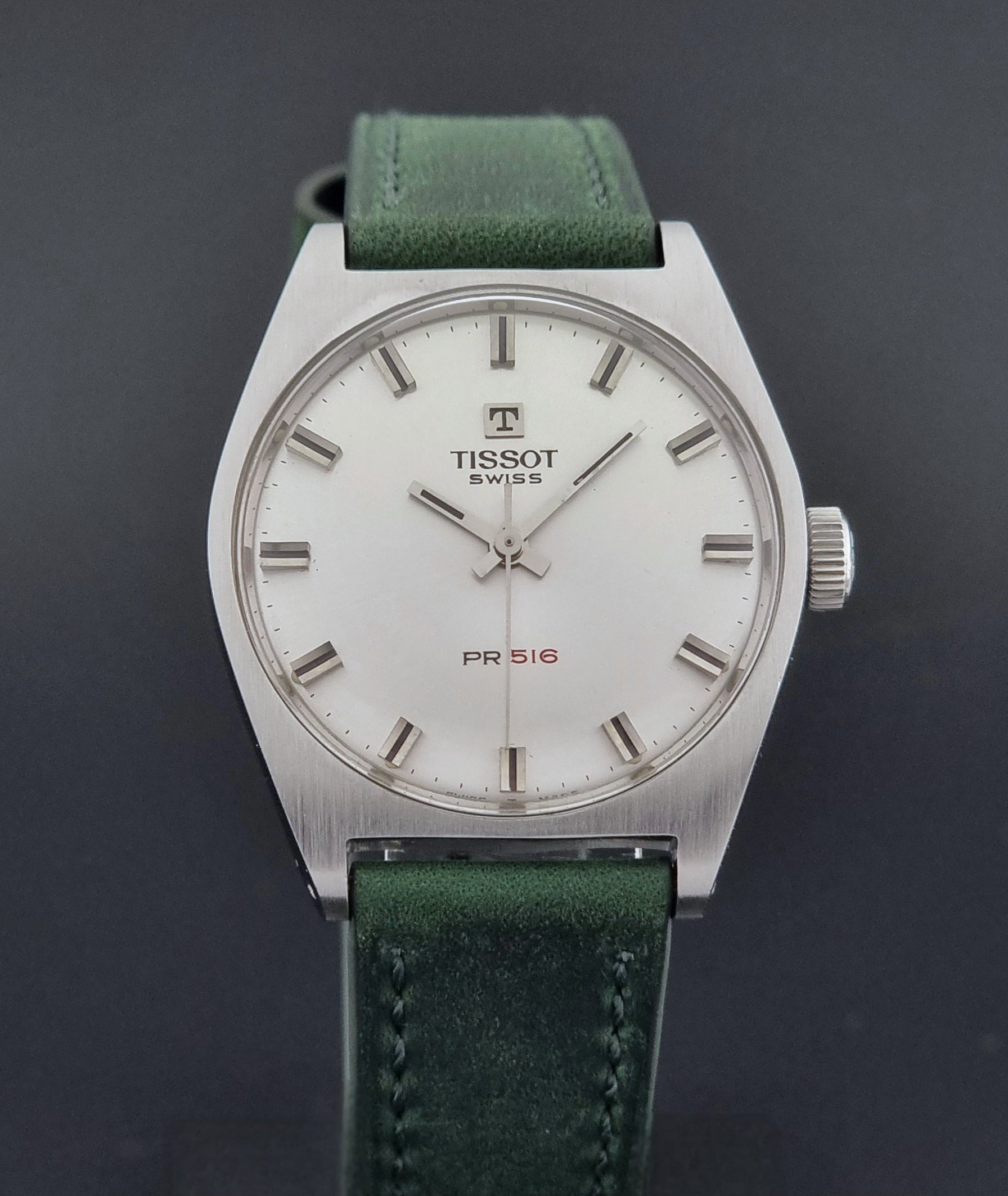 Vintage Tissot 41620 PR 516 wristwatch with green strap and silver case on a gray background close front view
