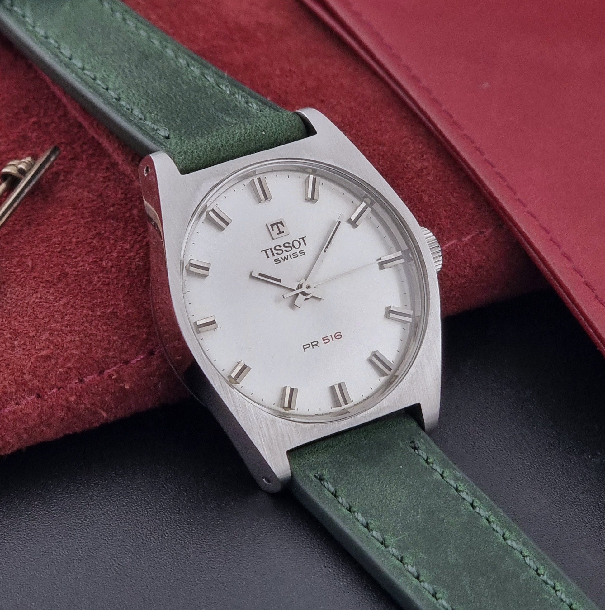 Vintage Tissot 41620 PR 516 wristwatch with green strap and silver case on a gray background side view