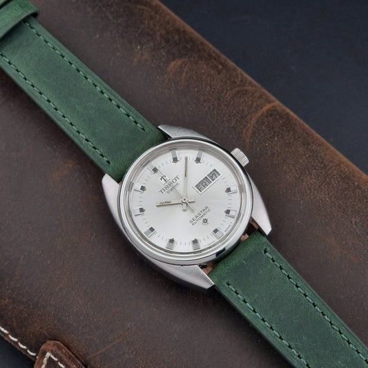 Tissot Seastar 46660 Watch with green strap and silver case on a brown leather background